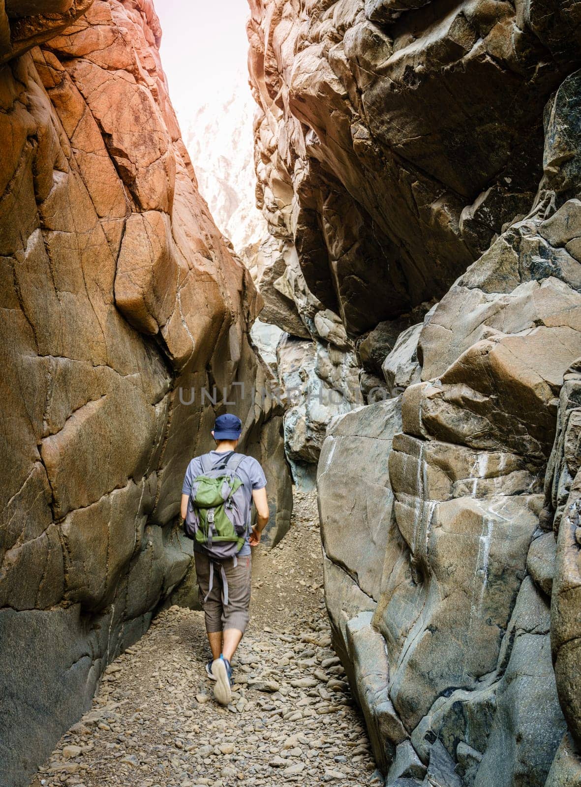 A man is hiking through a wadi in Hajar Mountains near Hatta, UAE