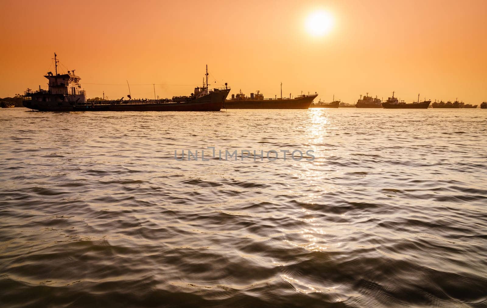 Commercial ships on anchorage in the Karnaphuli River in Bangladesh at sunset
