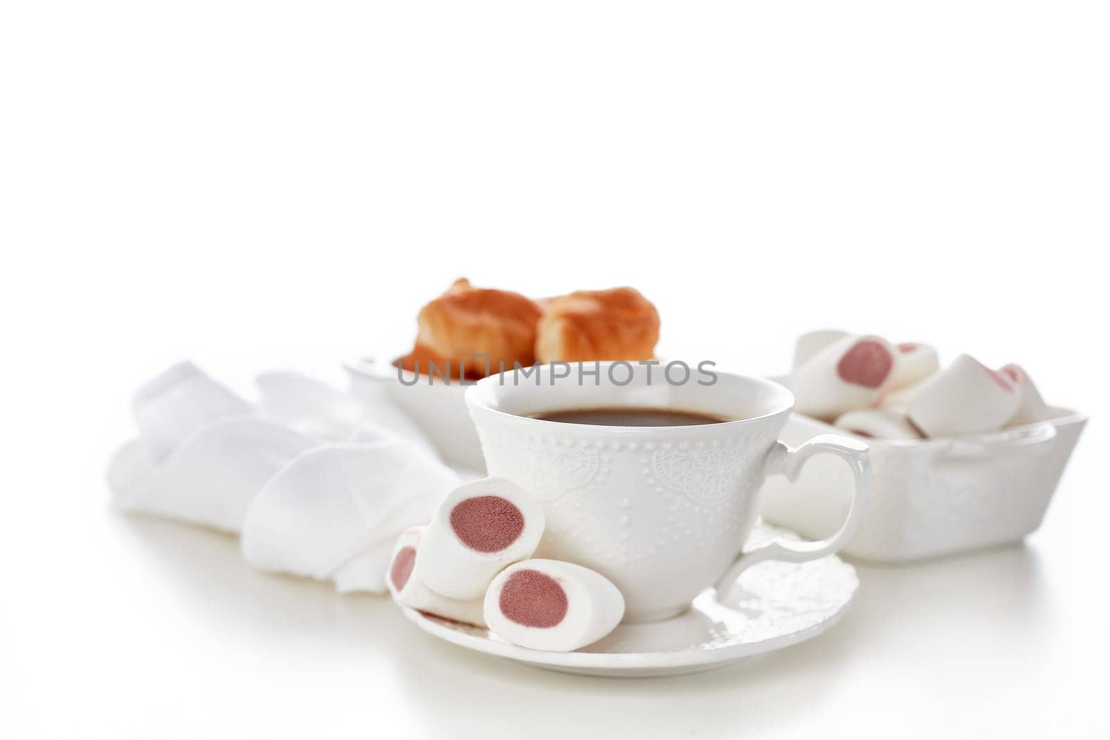 Sweet meal. Dessert. Still life with cup of coffee and bowls with marshmallows and croissants on white background.