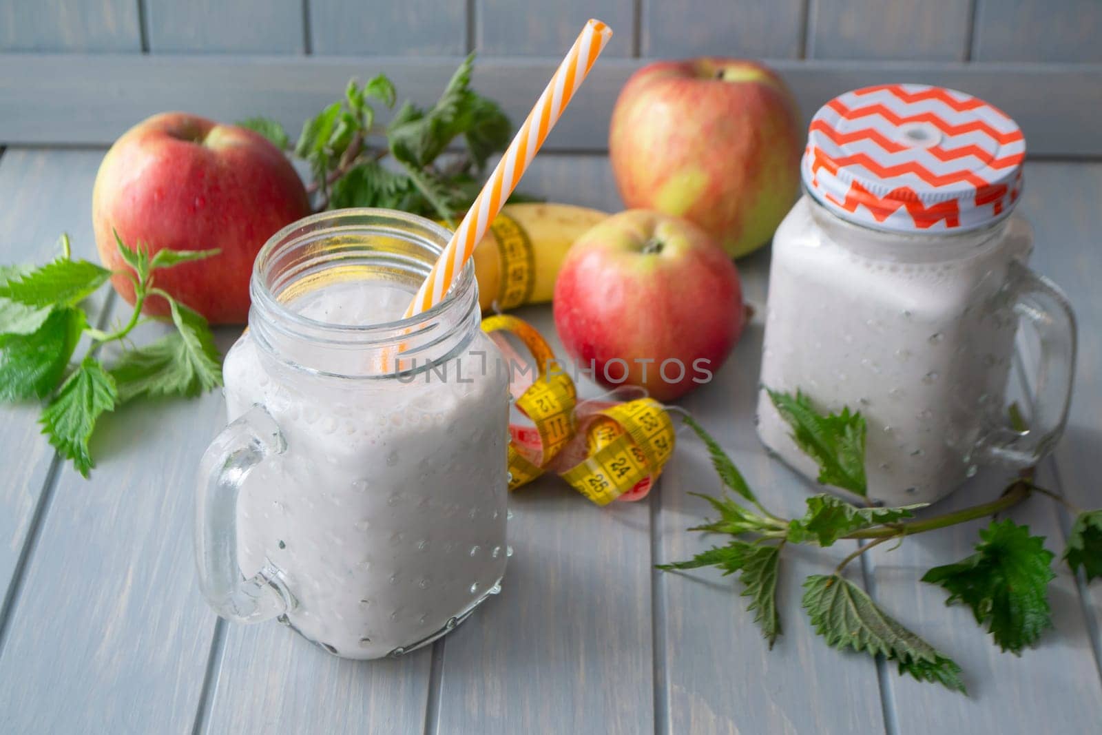 Healthy organic smoothie with apples, bananas and nettle on blue table