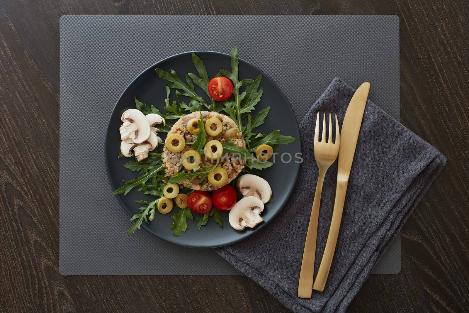 Healthy quinoa dish. Dietary salad with quinoa, mushrooms, arugula and olives. Healthy food, vegetarian menu. Top view. Setting table.