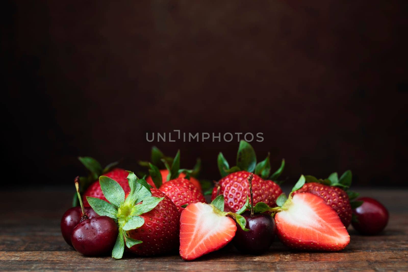 Strawberries and cherries on wooden table with copy space