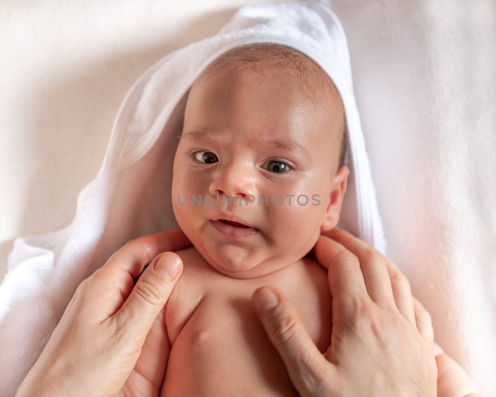 Adorable 2 months old little baby boy on towel after bath in his mother's hands