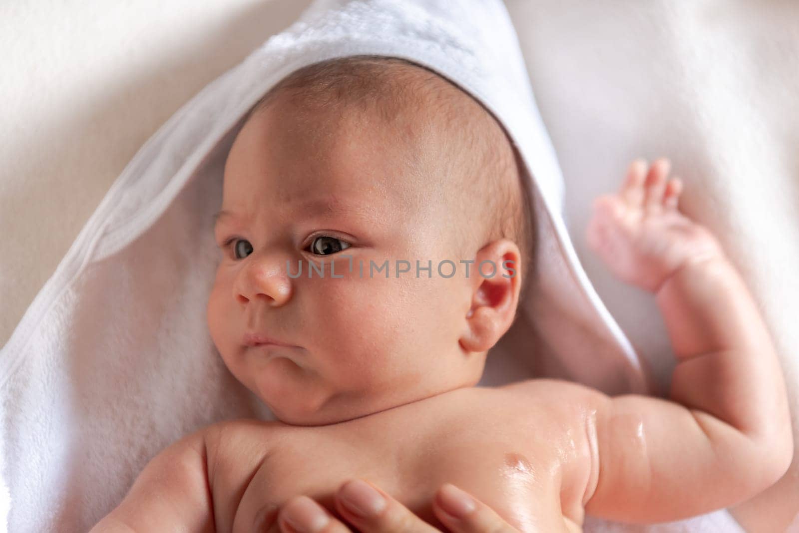 Adorable 2 months old little baby boy on towel after bath in his mother's hands