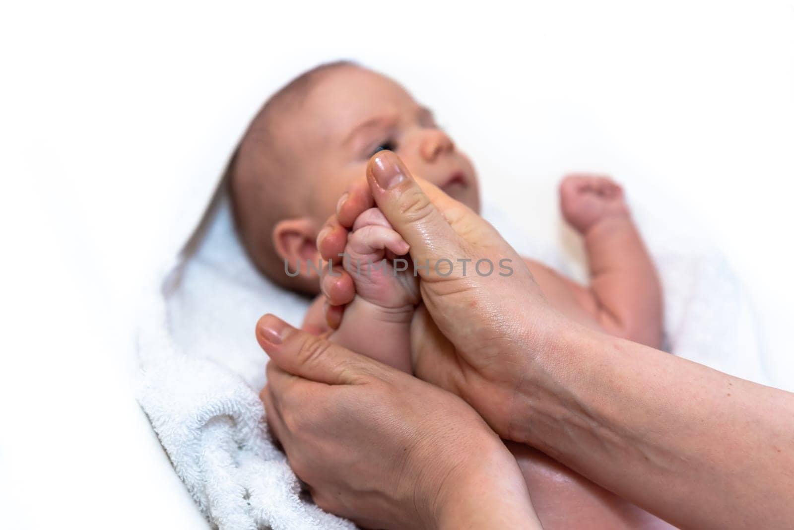 Adorable 2 months old little baby boy on towel after bath holding his mother's hands