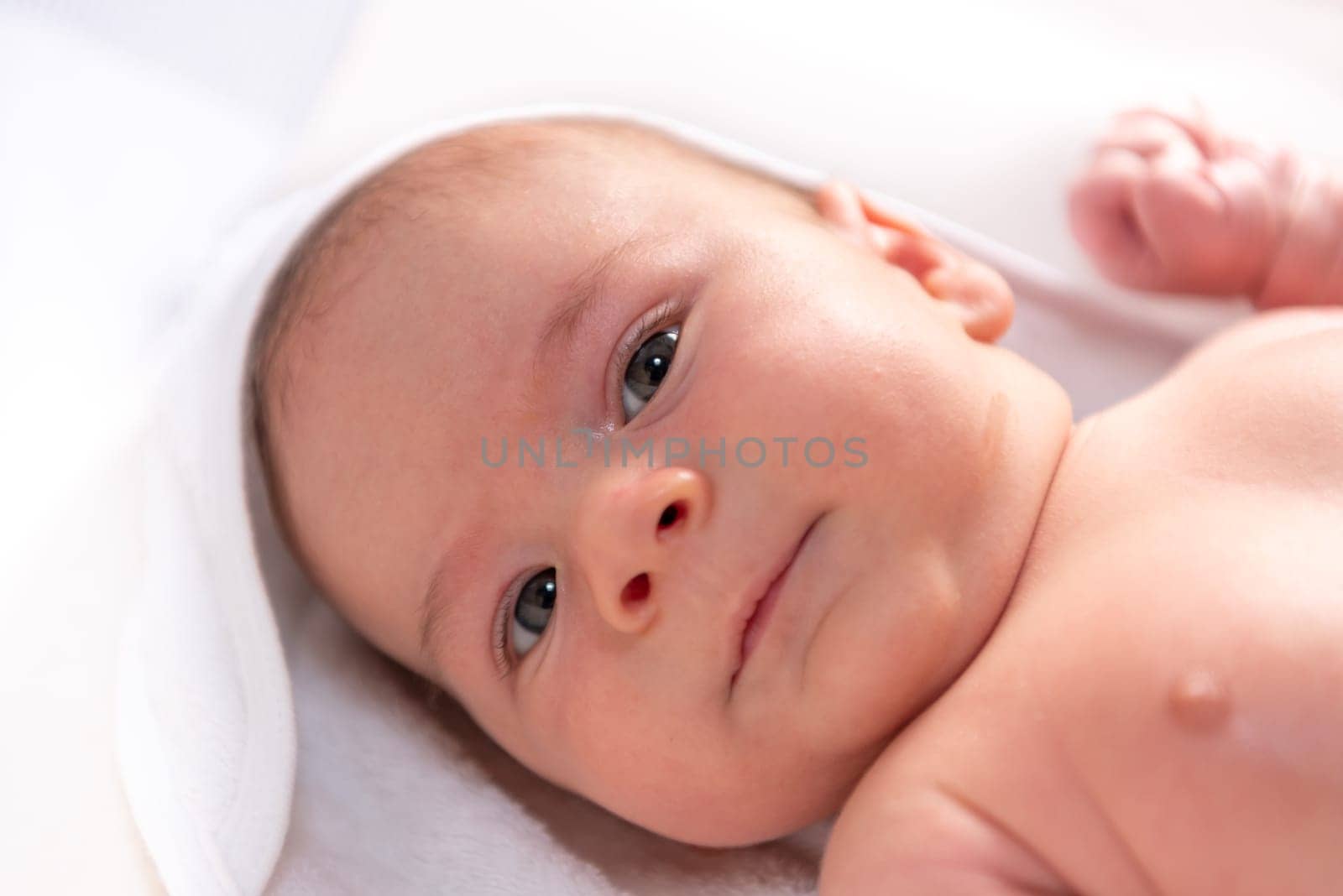 Adorable 2 months old little baby boy on towel after bath over white background