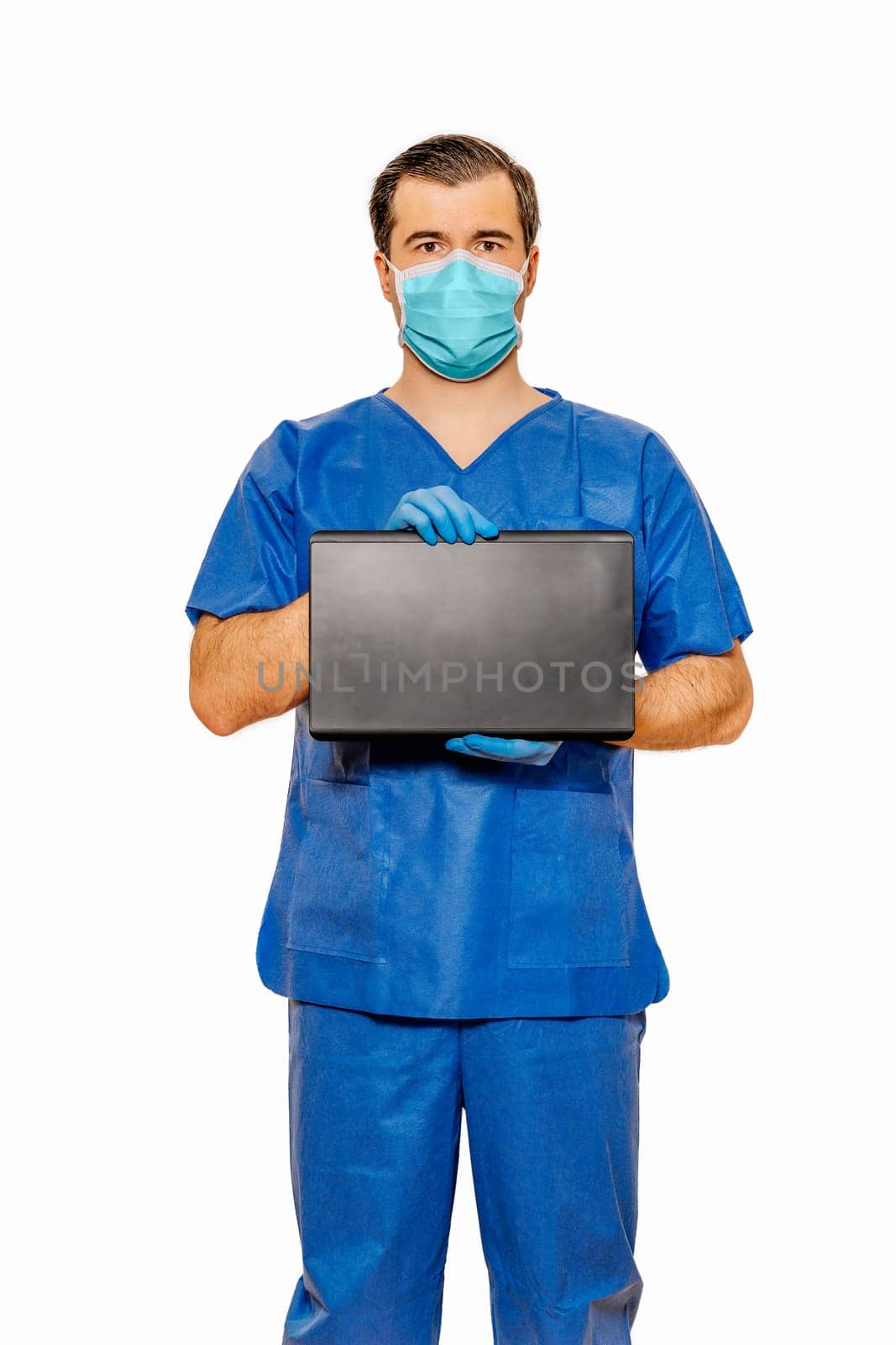 Male doctor in scrubs with protective face mask holding tablet with space for your text and creative ideas. Plain white background Coronavirus concept
