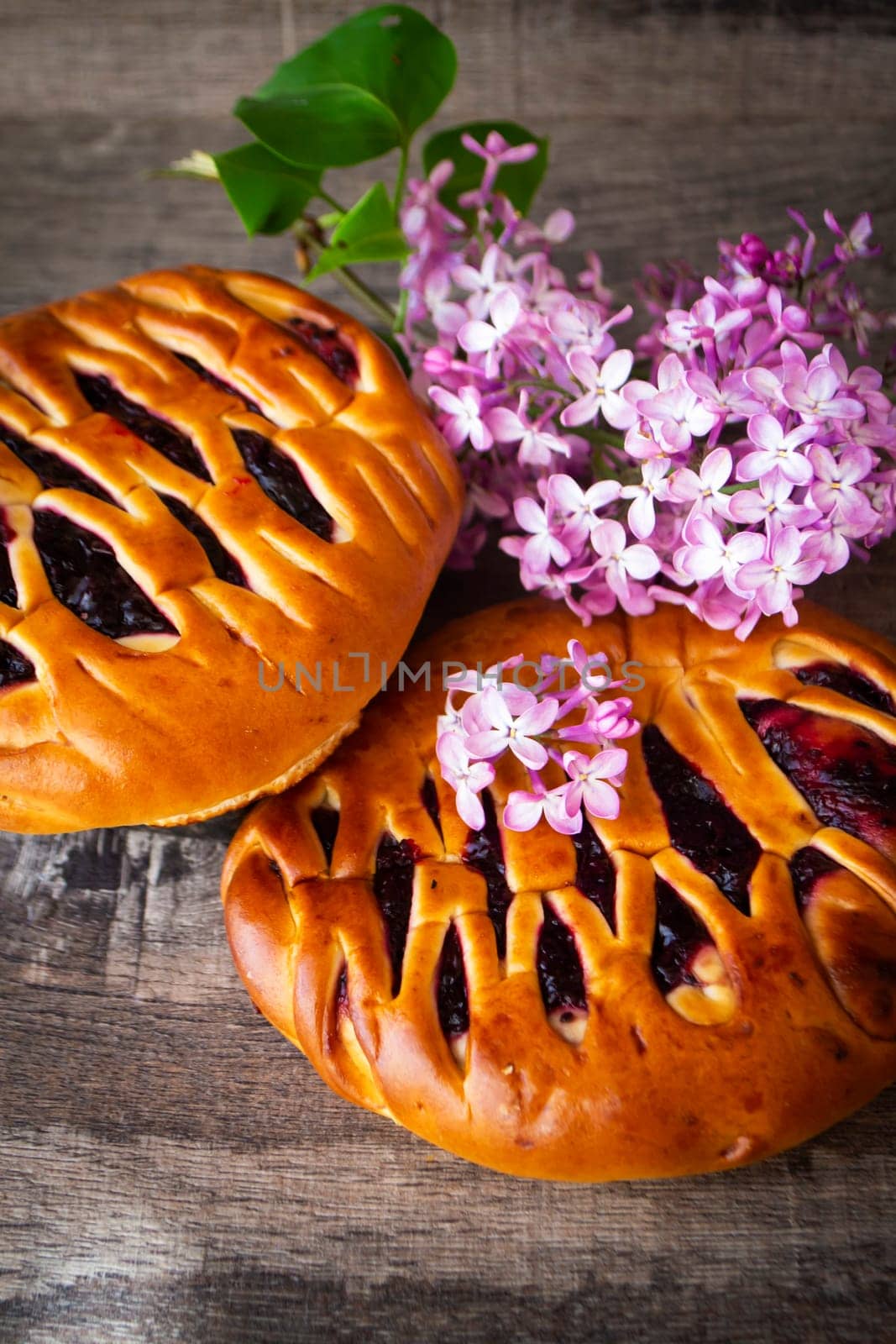 Brioche dough with blackcurrant, with violet lilac flowers, vertical image