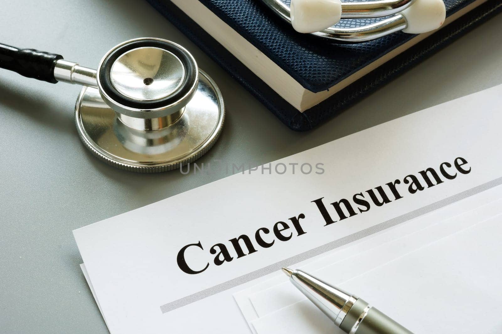Cancer Insurance policy and stethoscope on a desk.