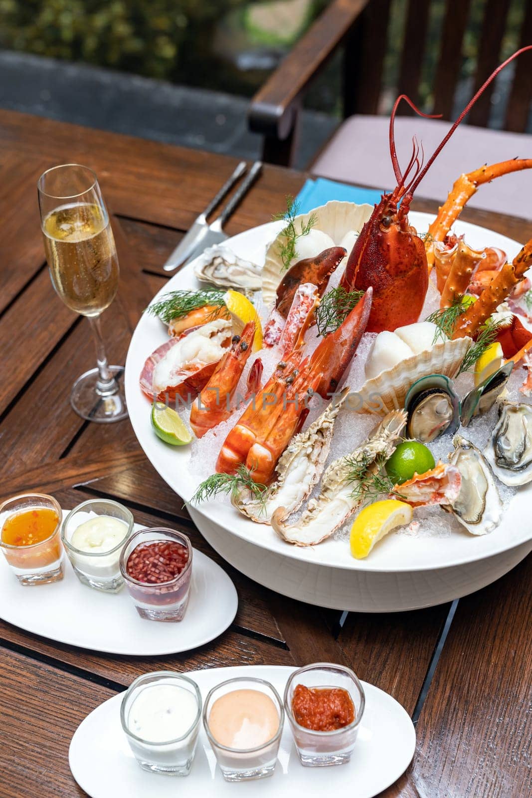 Bowl of gourmet fresh seafood on ice with savory sauce serve with white wine glass on vintage wooden table. Restaurant gastronomy food and drink consumerism concept.