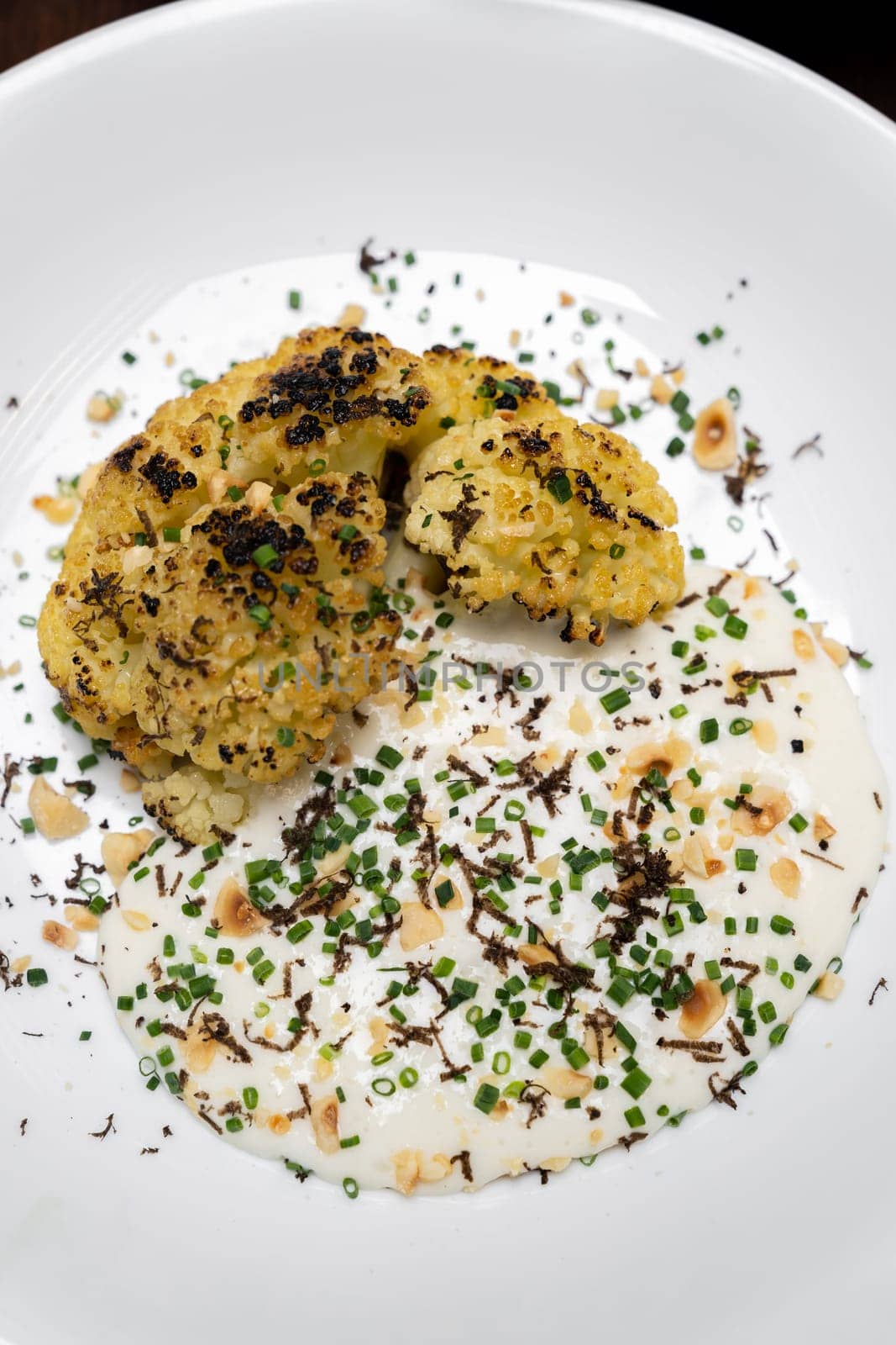 Roasted Cauliflower with Parmesan and Hazelnut topping with spring onion and cauliflower soup, gourmet international cuisine recipe. Restaurant gastronomy food and drink consumerism concept.