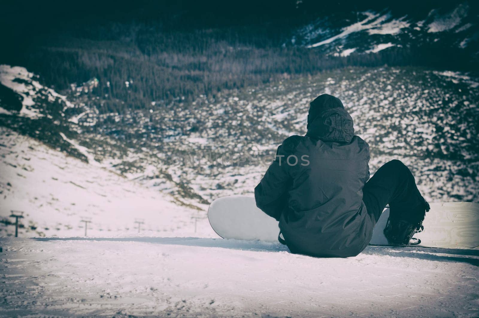 snowboarder sitting with mountain chain in the background