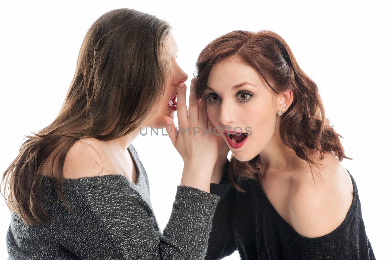 Girl whispers girlfriend something in the ear