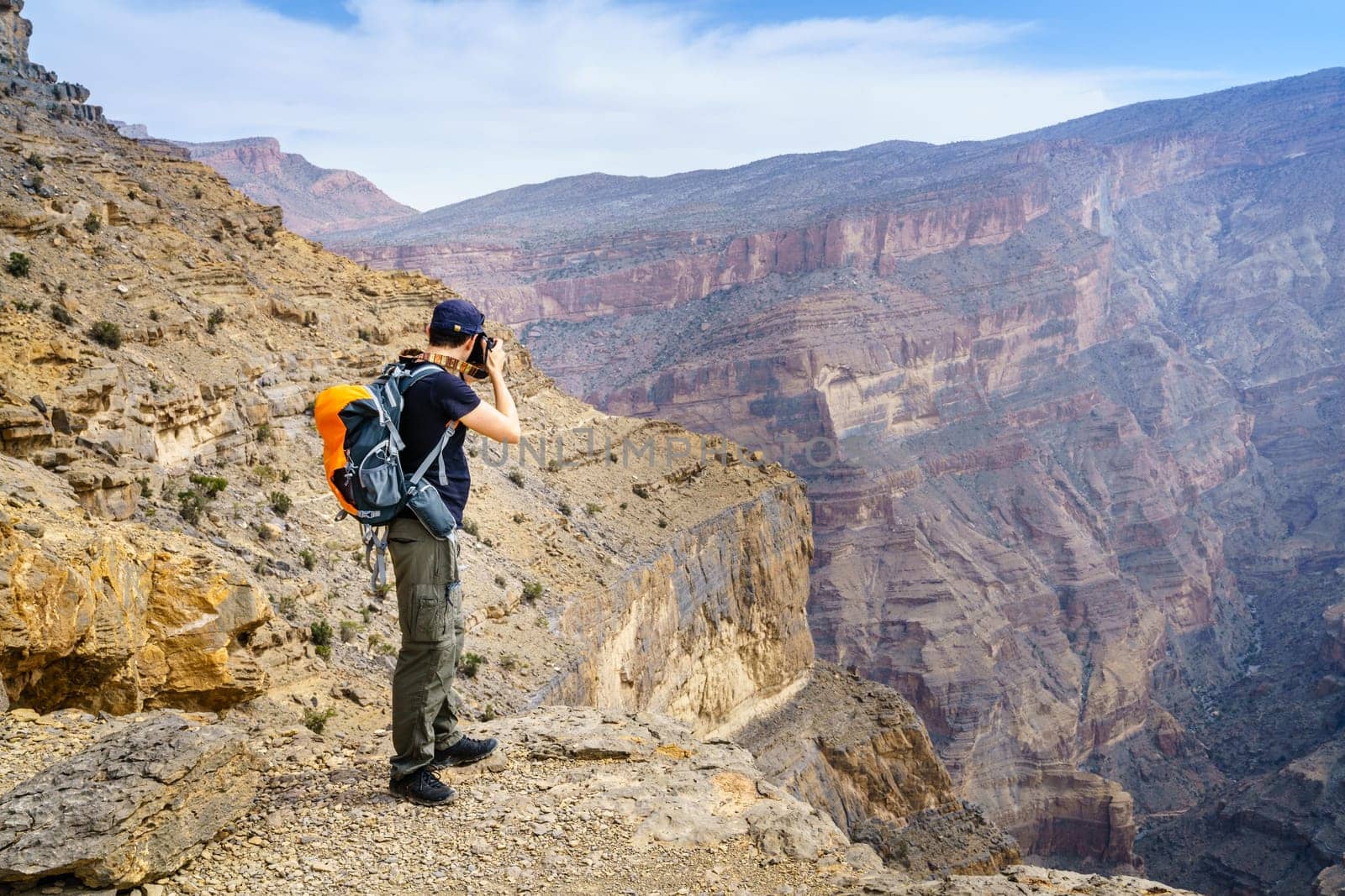 Man is taking phots of the canyon in Jebel Shams Mountain in Oman