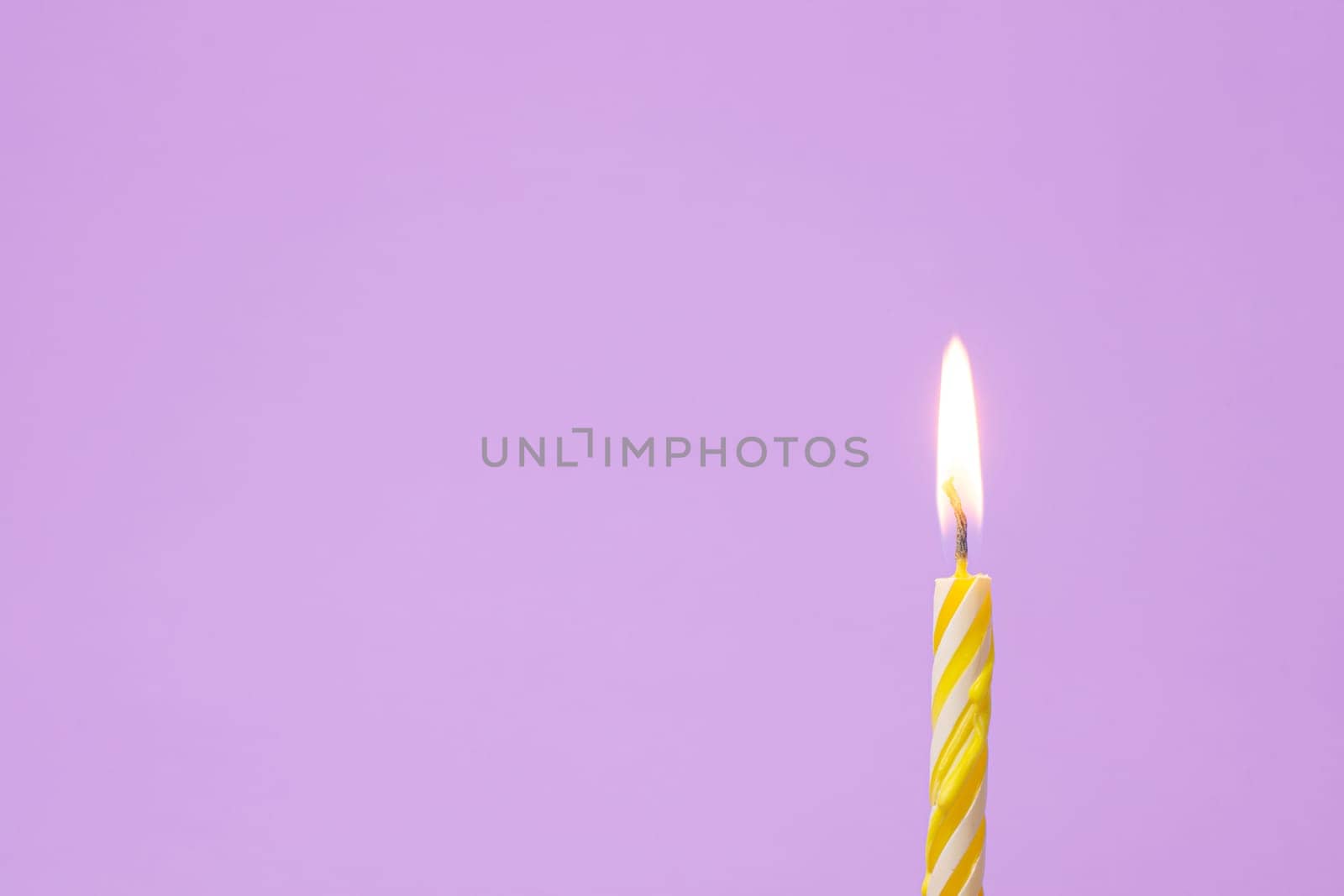 One festive candle is lit, light purple background