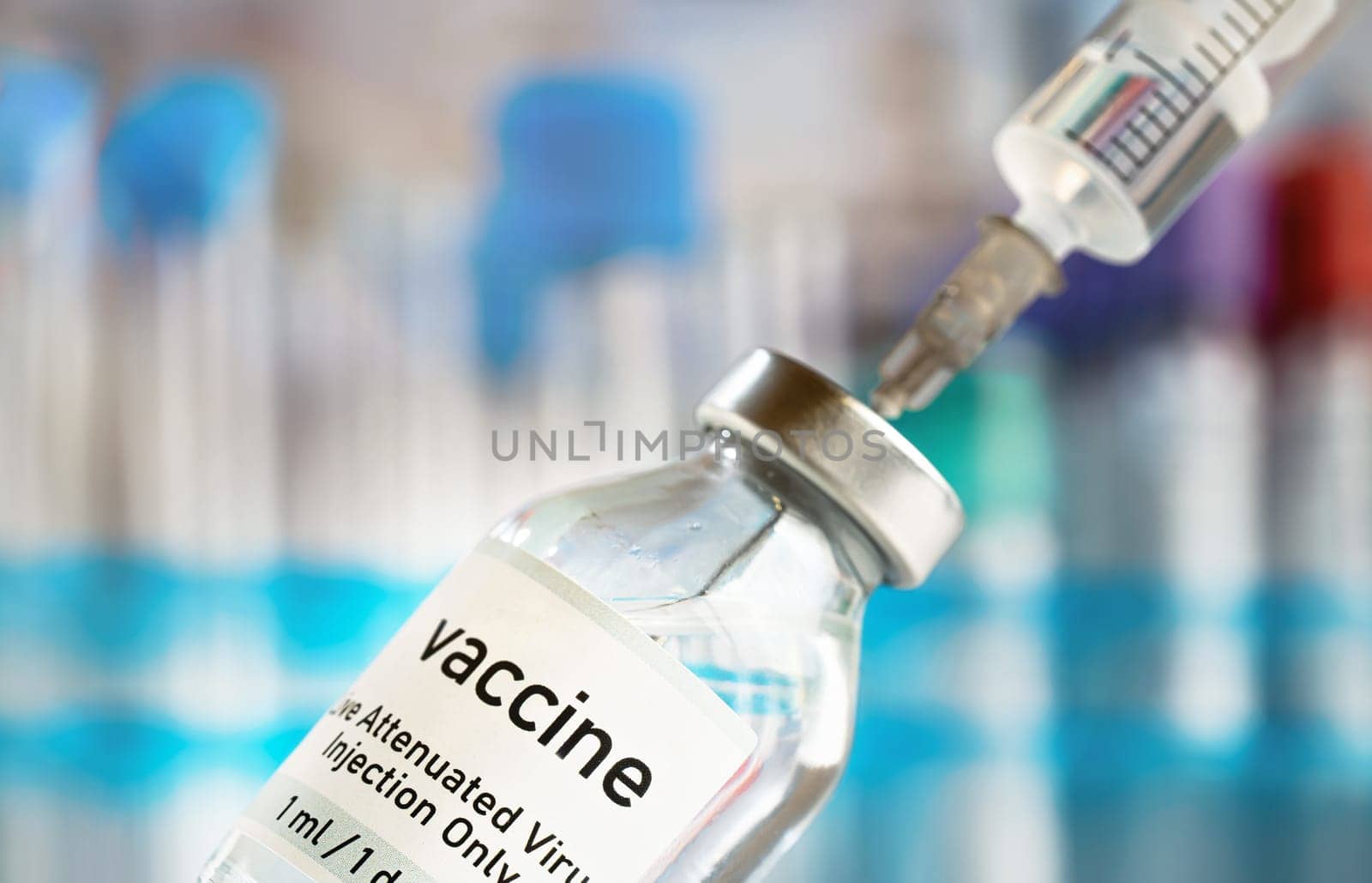 Vaccine glass bottle with syringe injected, blurred vials background.