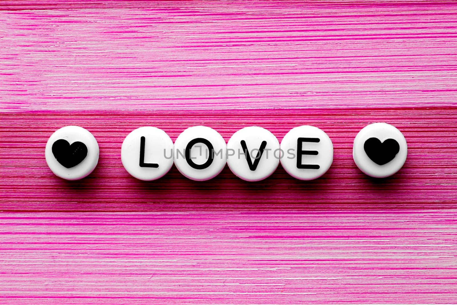 Love text with hearts on the side on a pink wooden table