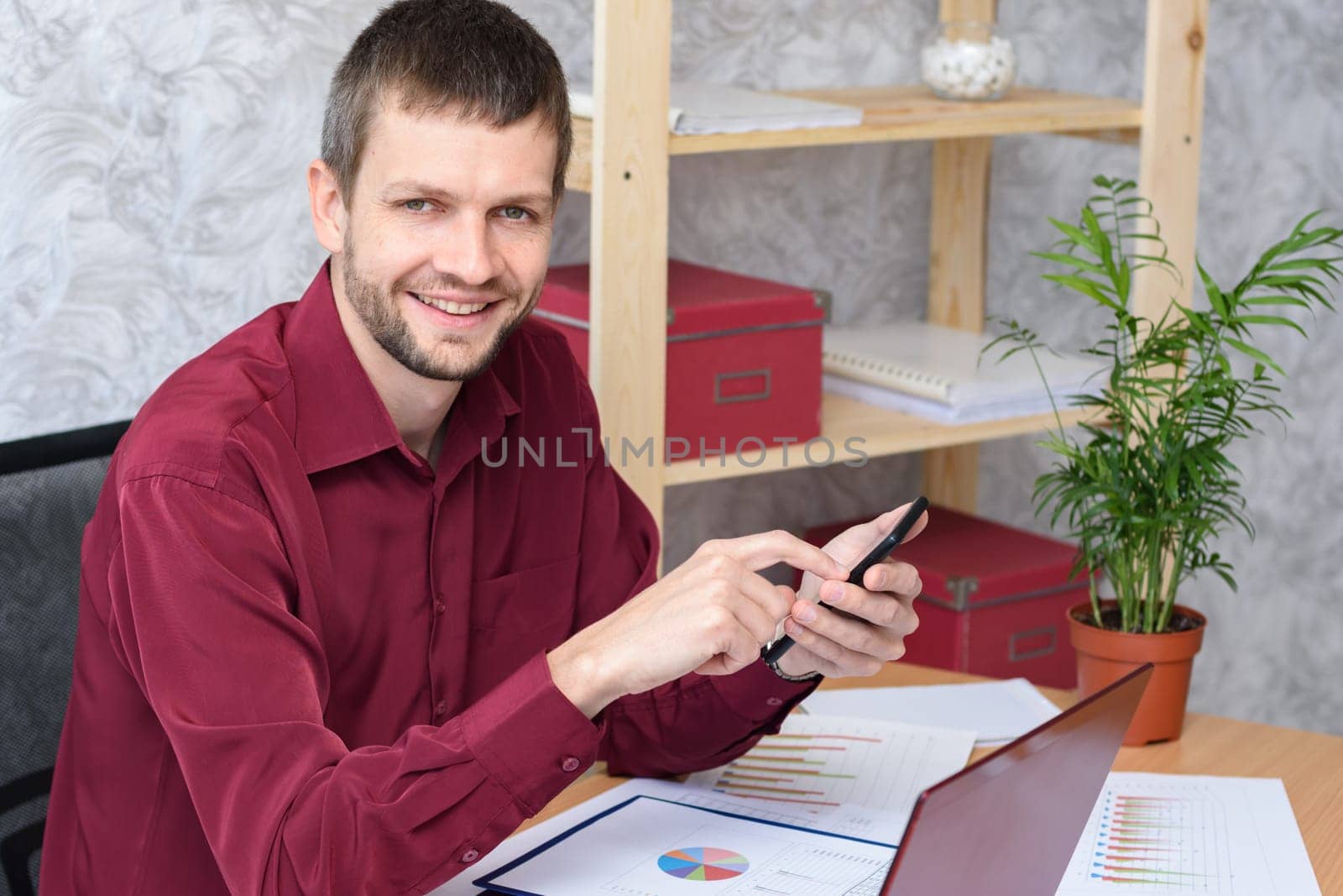 Smiling office worker corresponds on his smartphone