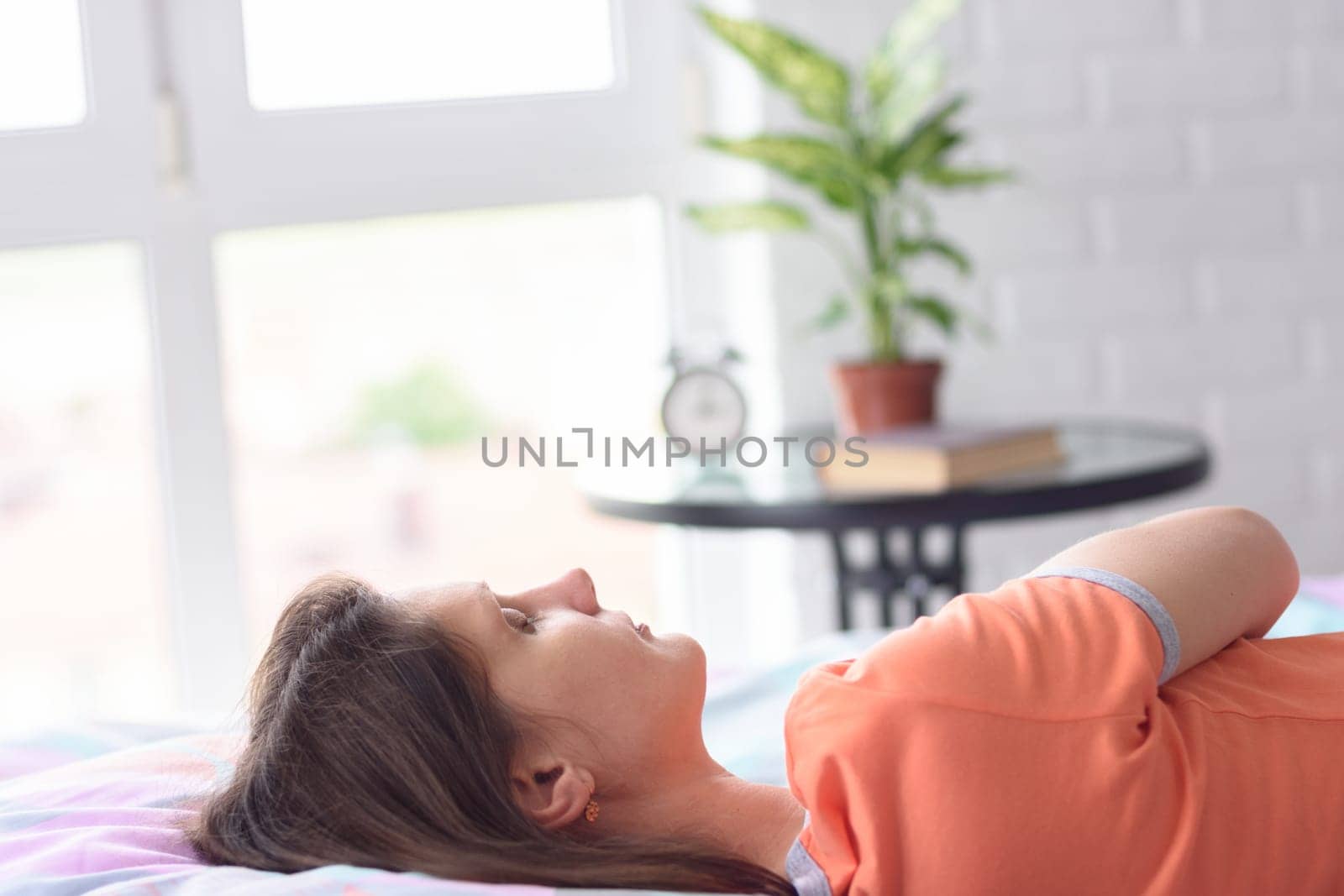 Girl sleeps in bed against the background of a window, close-up