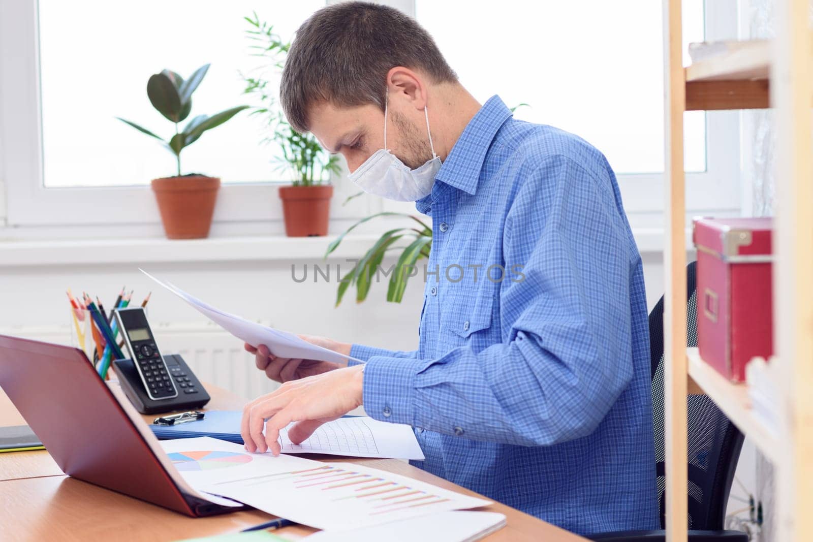 office worker in medical mask disassembles documents on the desktop