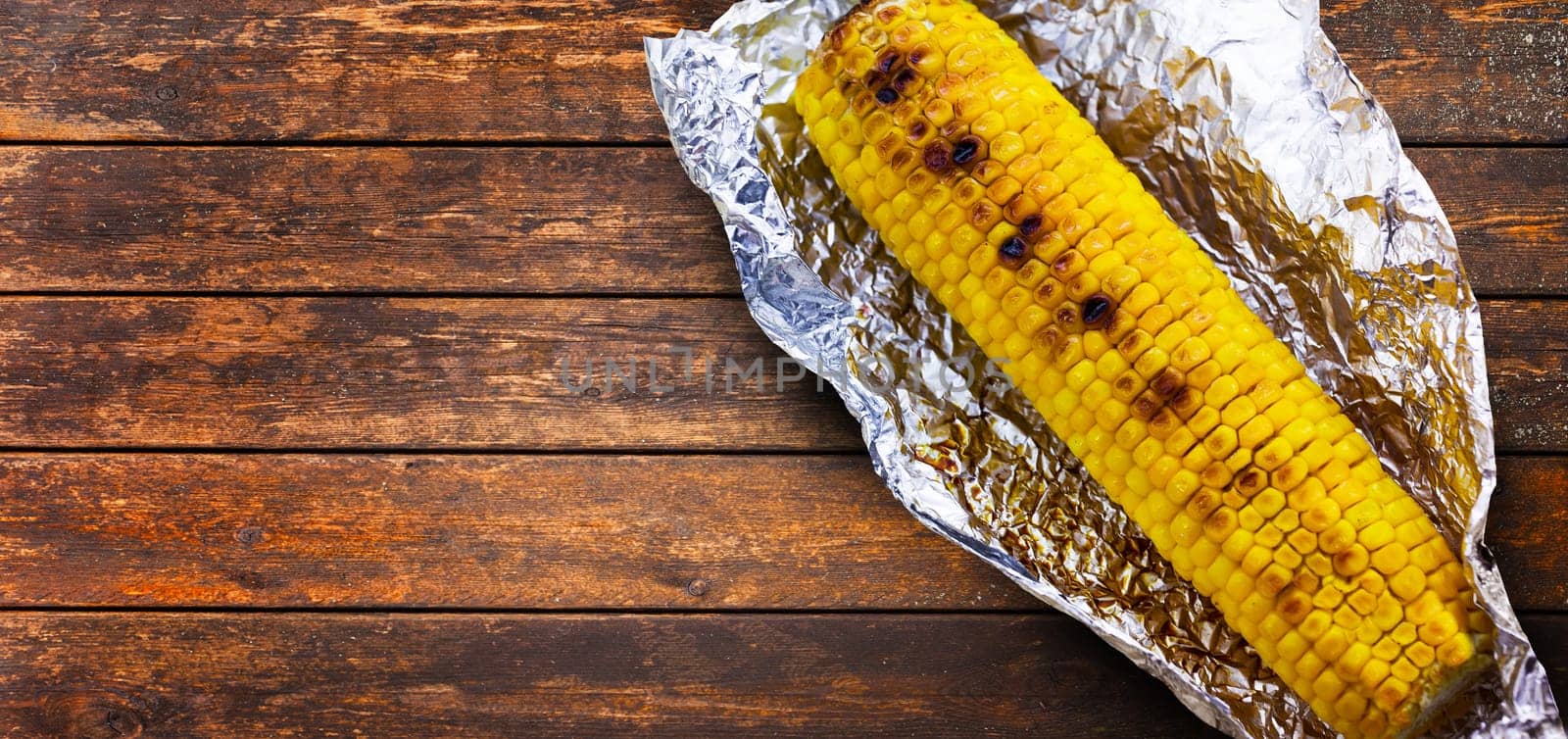Tasty grilled corn on brown wooden table