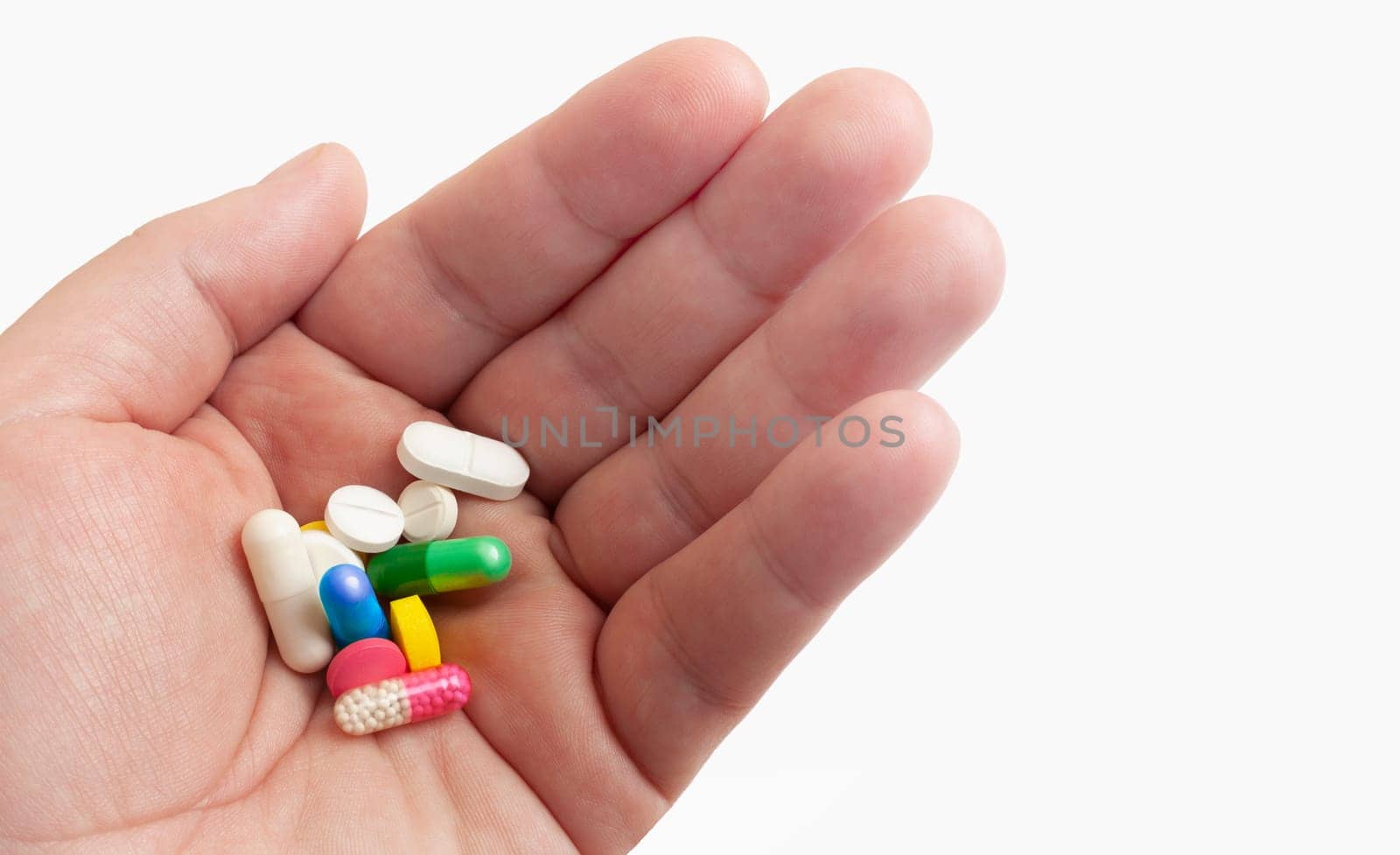 Man holds medicine pills in hand before taking them. Isolated on white background