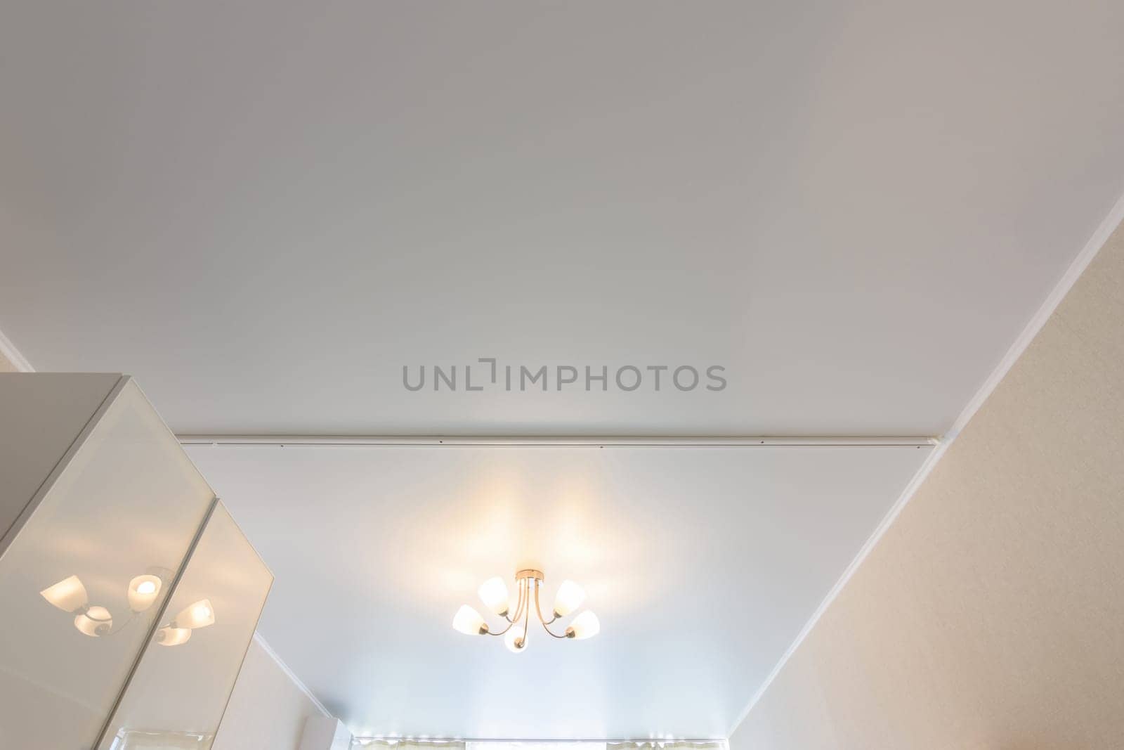 Classic white matte stretch ceiling with five lamp chandelier in the center