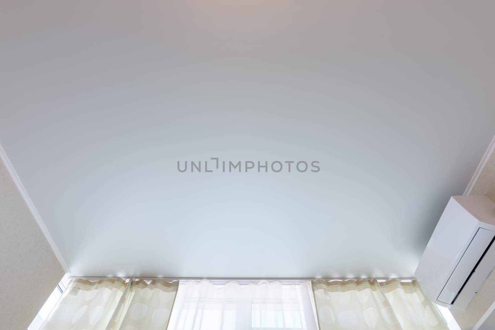 Fragment of a classic stretch ceiling above a window in a room