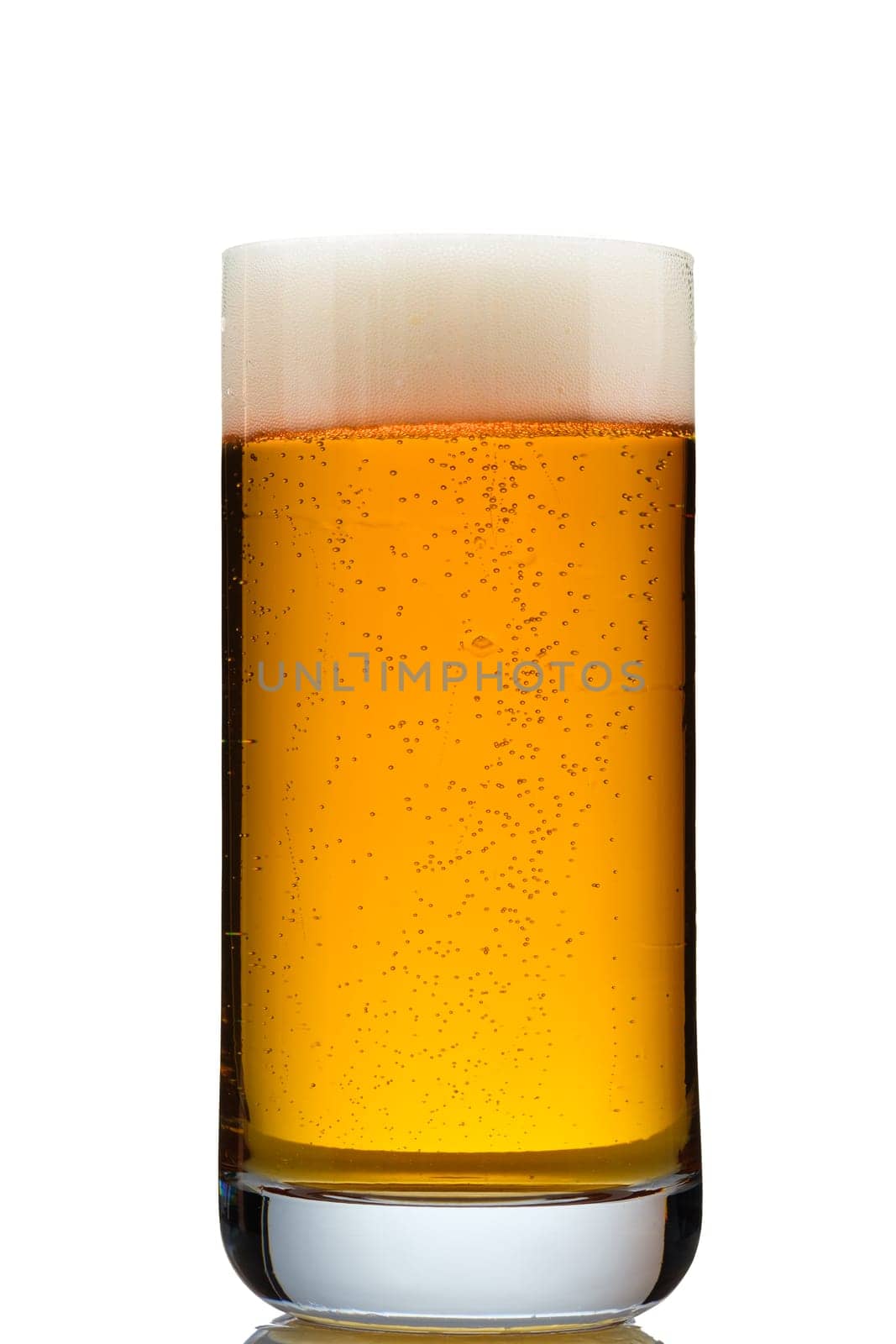 Golden beer with foam in a translucent glass close-up