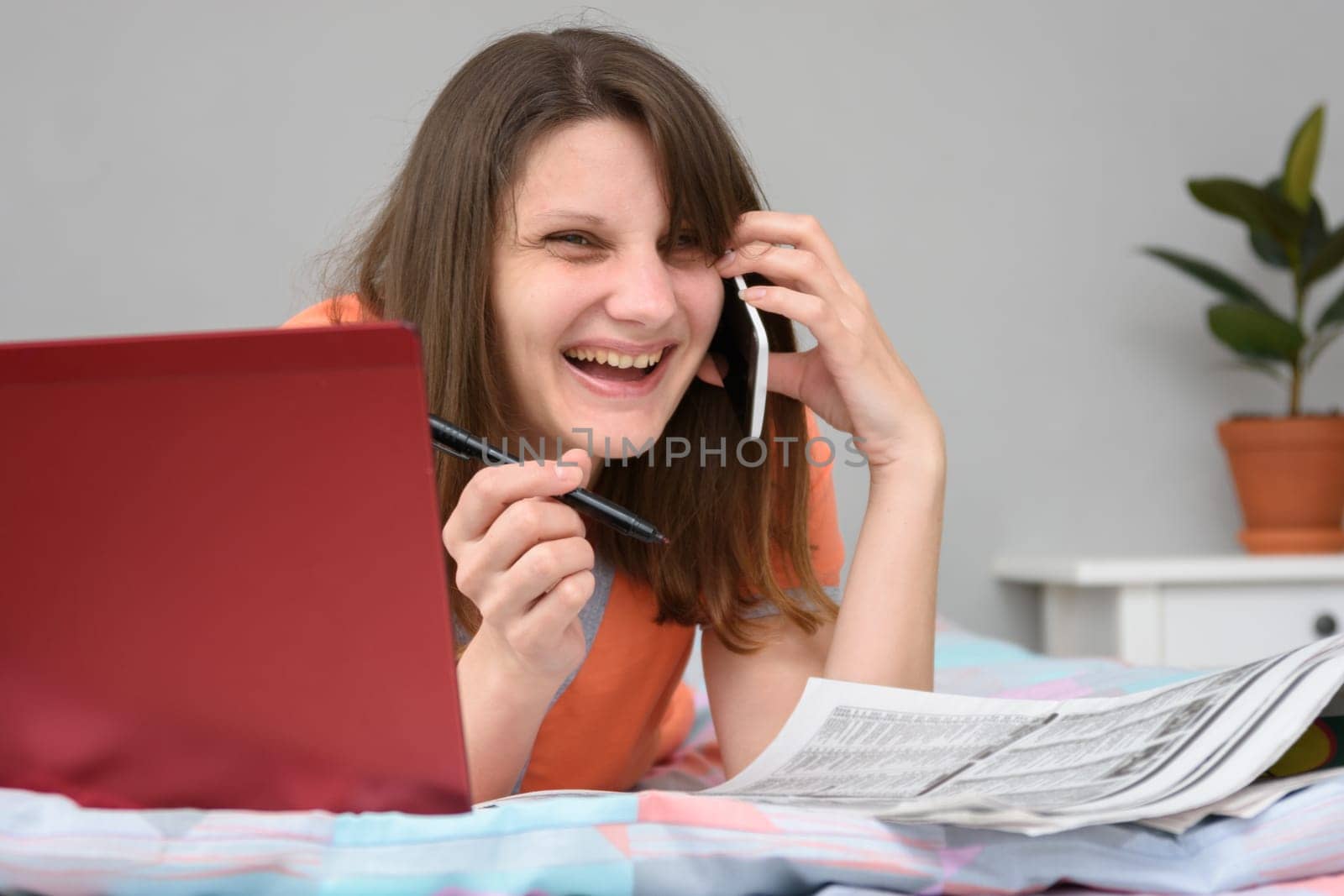 Girl laughs a lot while talking with the employer on the phone and looking for work