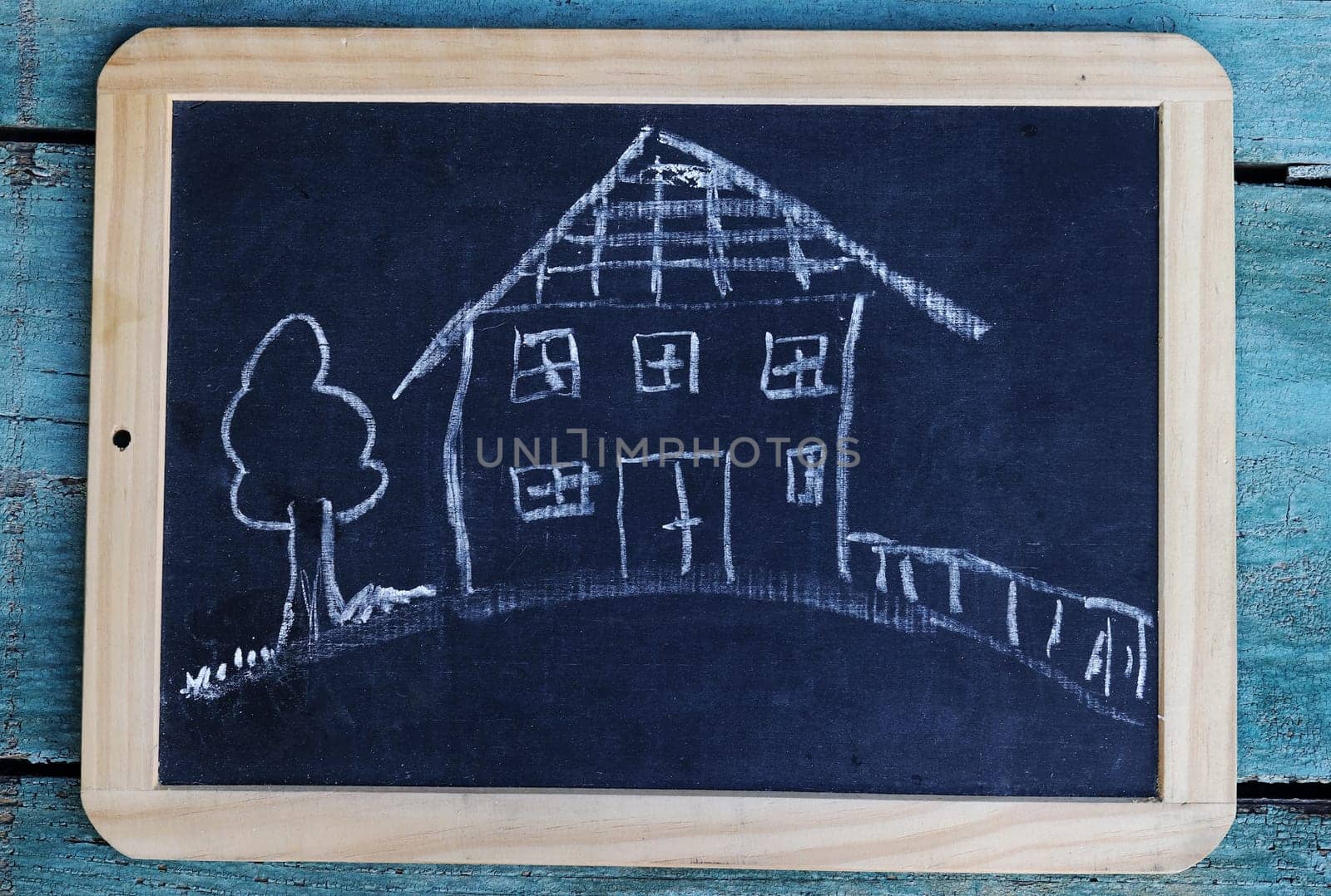 A blackboard with a drawing of a house with garden