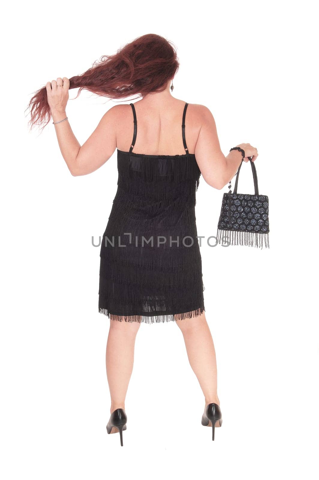 A beautiful woman standing in a black dress from the back with her long.red hair, isolated for white background.