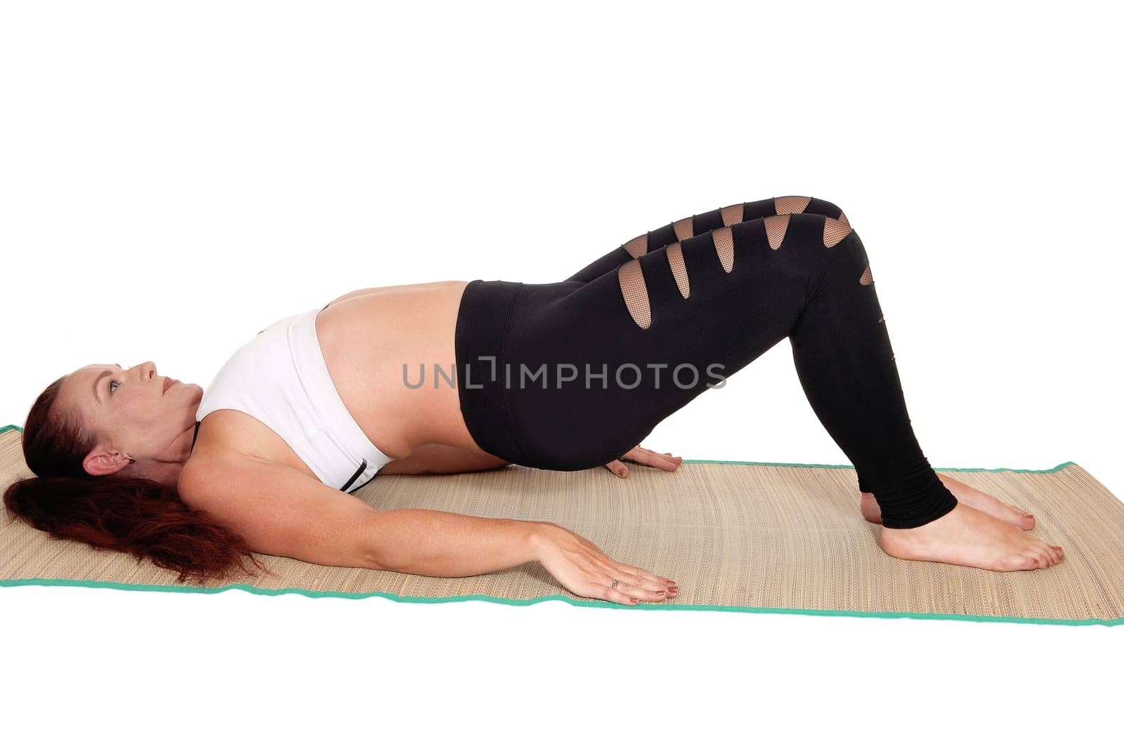 A middle age woman in sports outfit lying on the back lifting her butt.up, with her red hair and nice figure, isolated for white background.