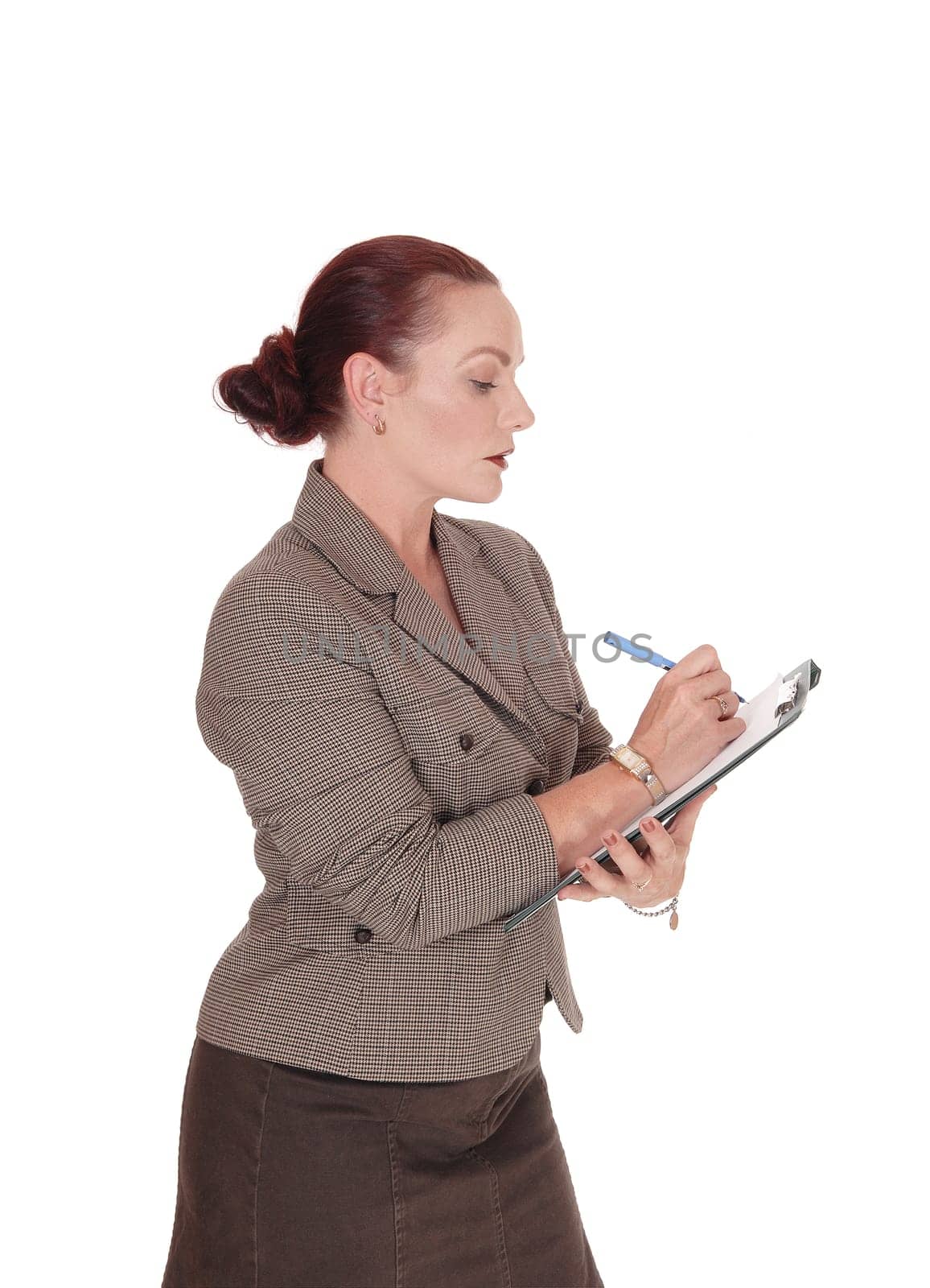 A serious looking business woman writing on her clipboard with a  .blue pen, isolated for white background.