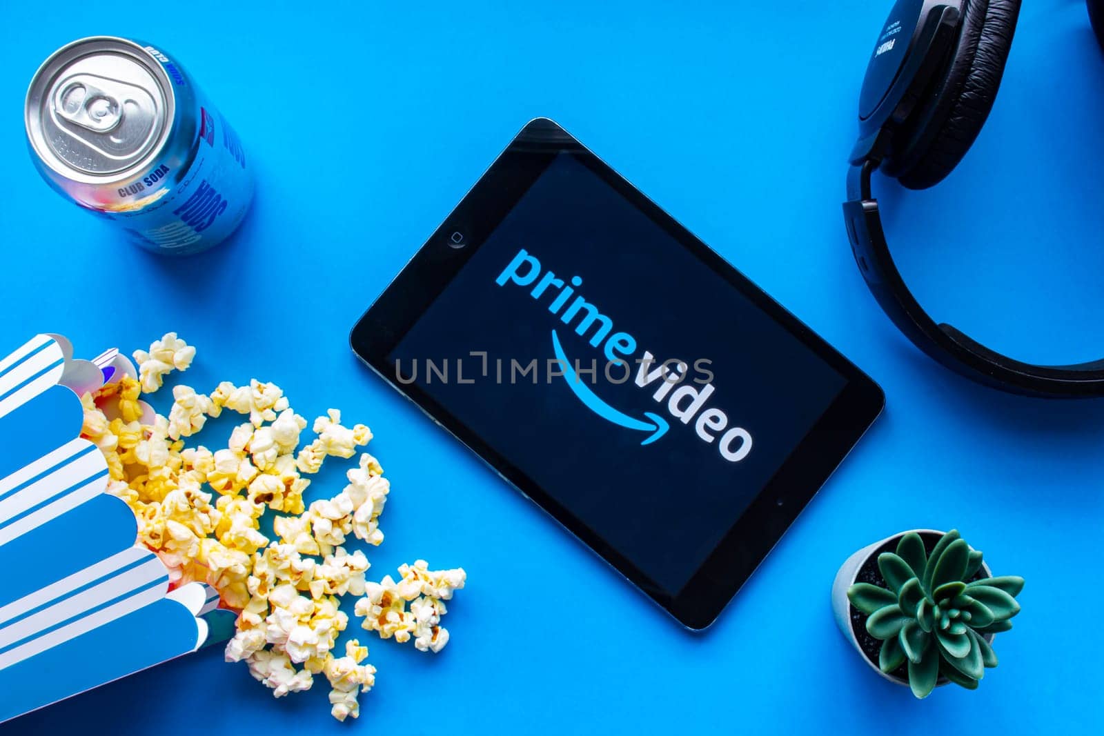 Calgary, Alberta. Canada. June 1 2020. An iPad with the Prime Video logo on the screen on a blue background with popcorn and headphones