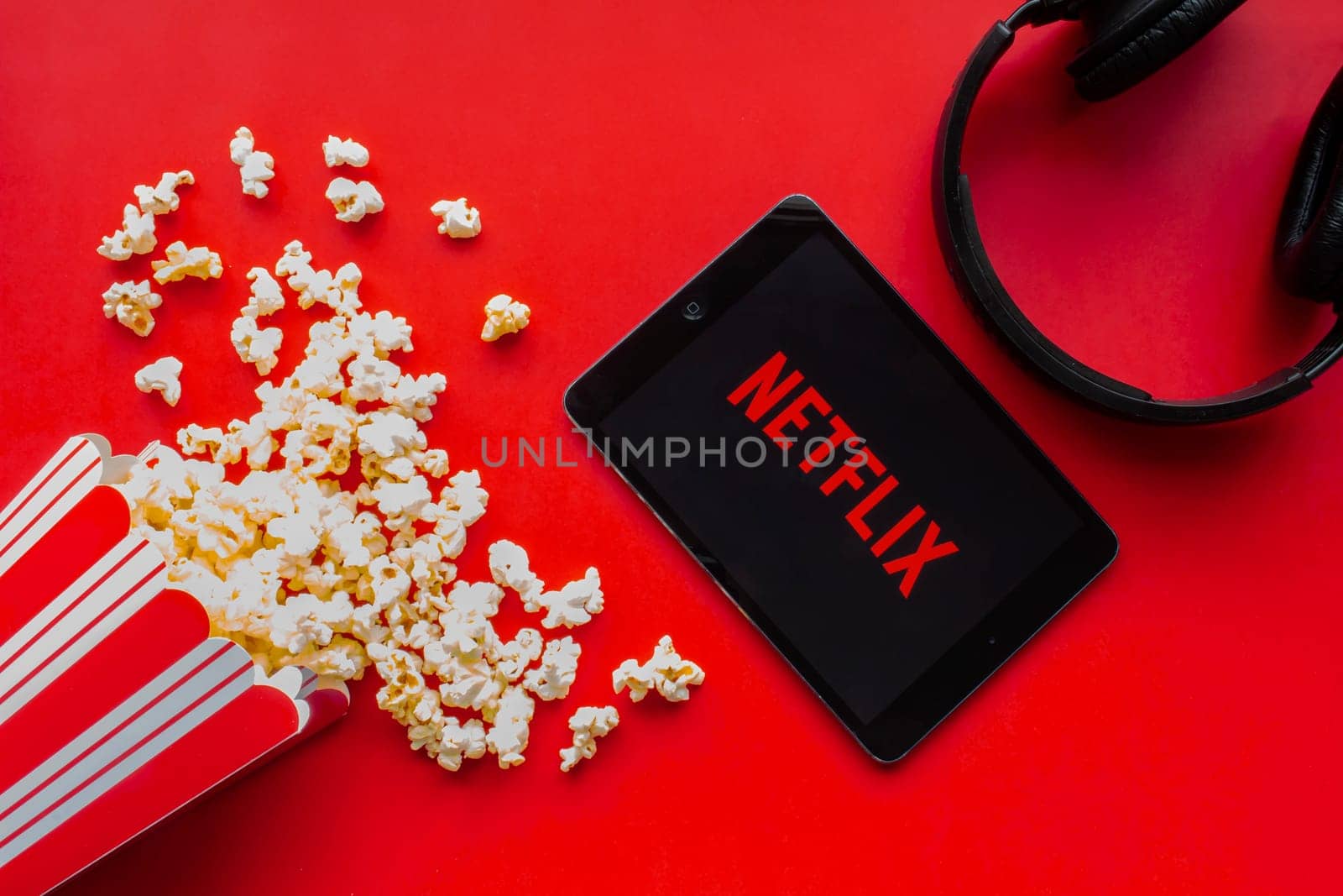 Calgary, Alberta. Canada. June 1 2020. An iPad with the Netflix logo on the screen on a red background with popcorn and headphones