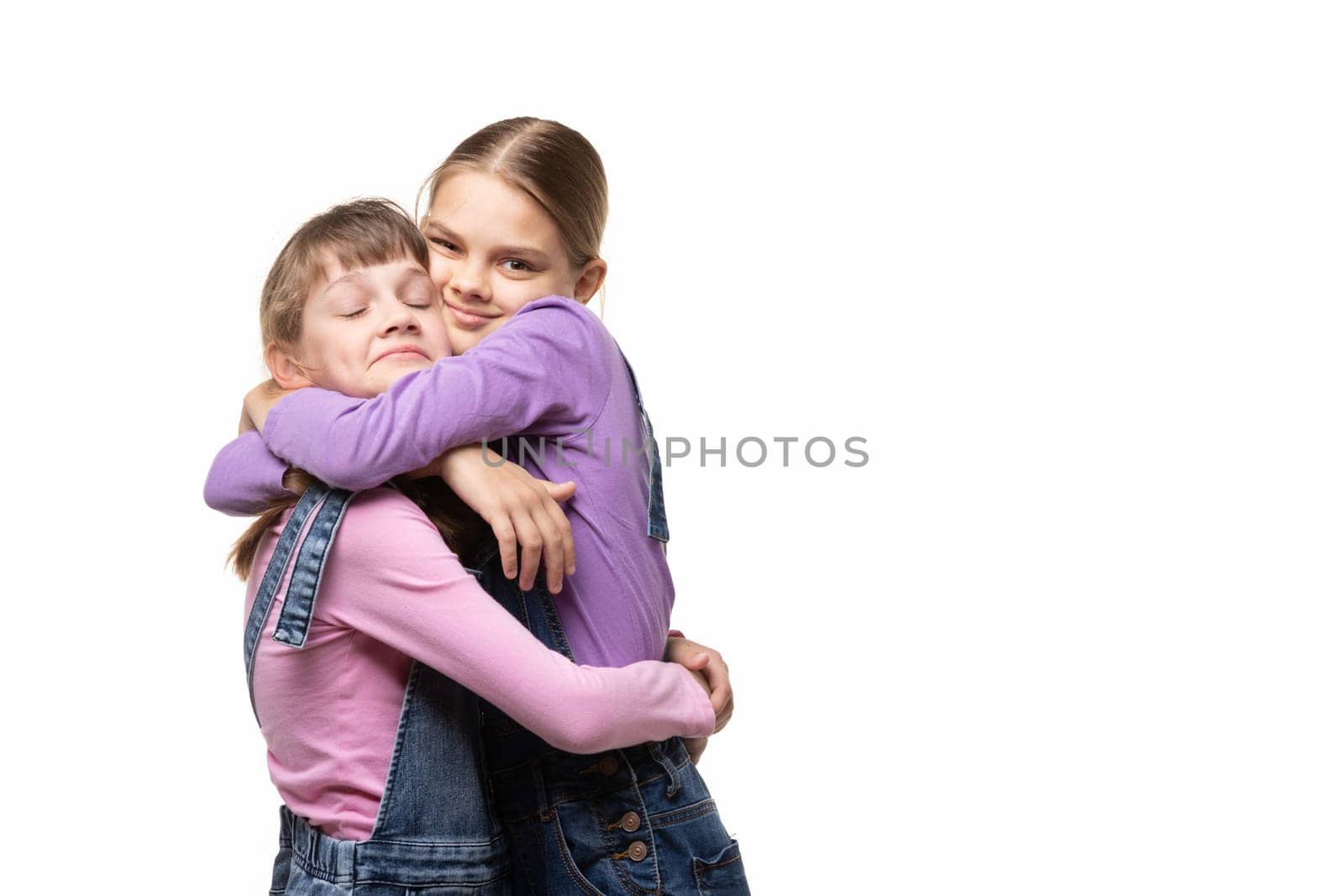 Two girlfriends happily hug each other, white background