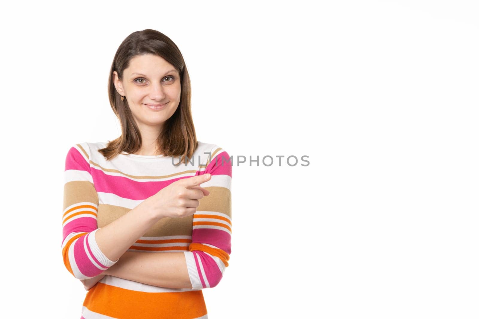 Girl with a charming smile points a finger to an empty place, white background