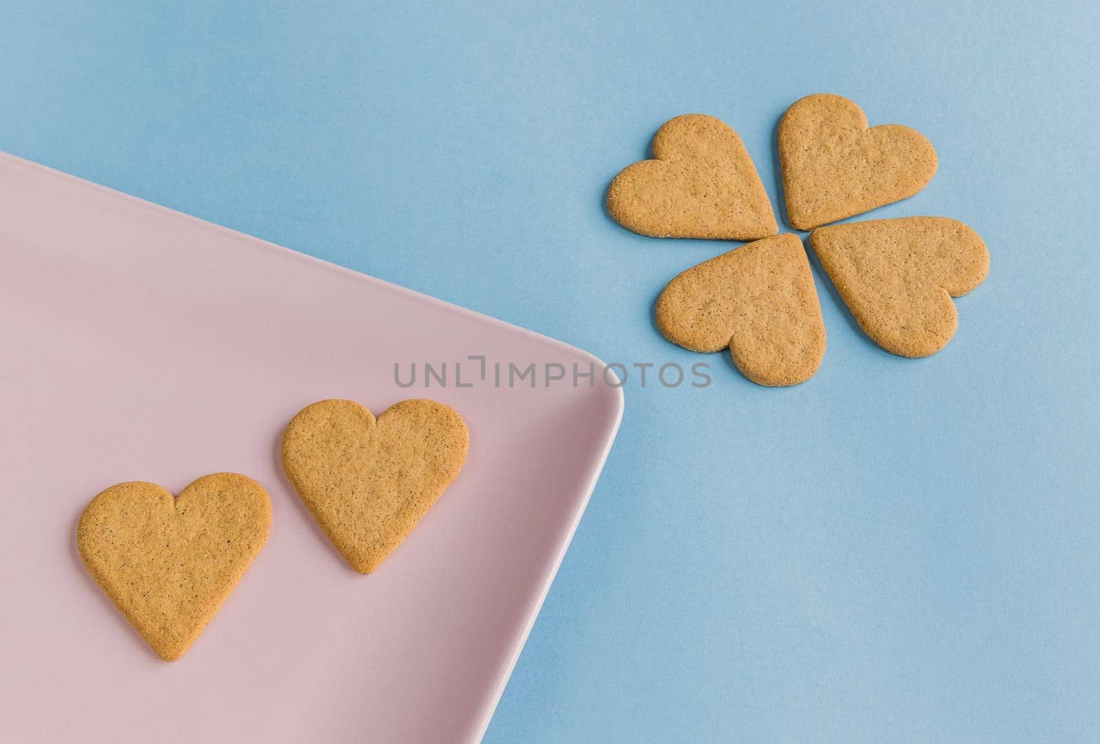 Breakfast. Close-up of heart shaped on a pink tray. Cookies like a flower petals.. Blue background. Copy space.Copy space