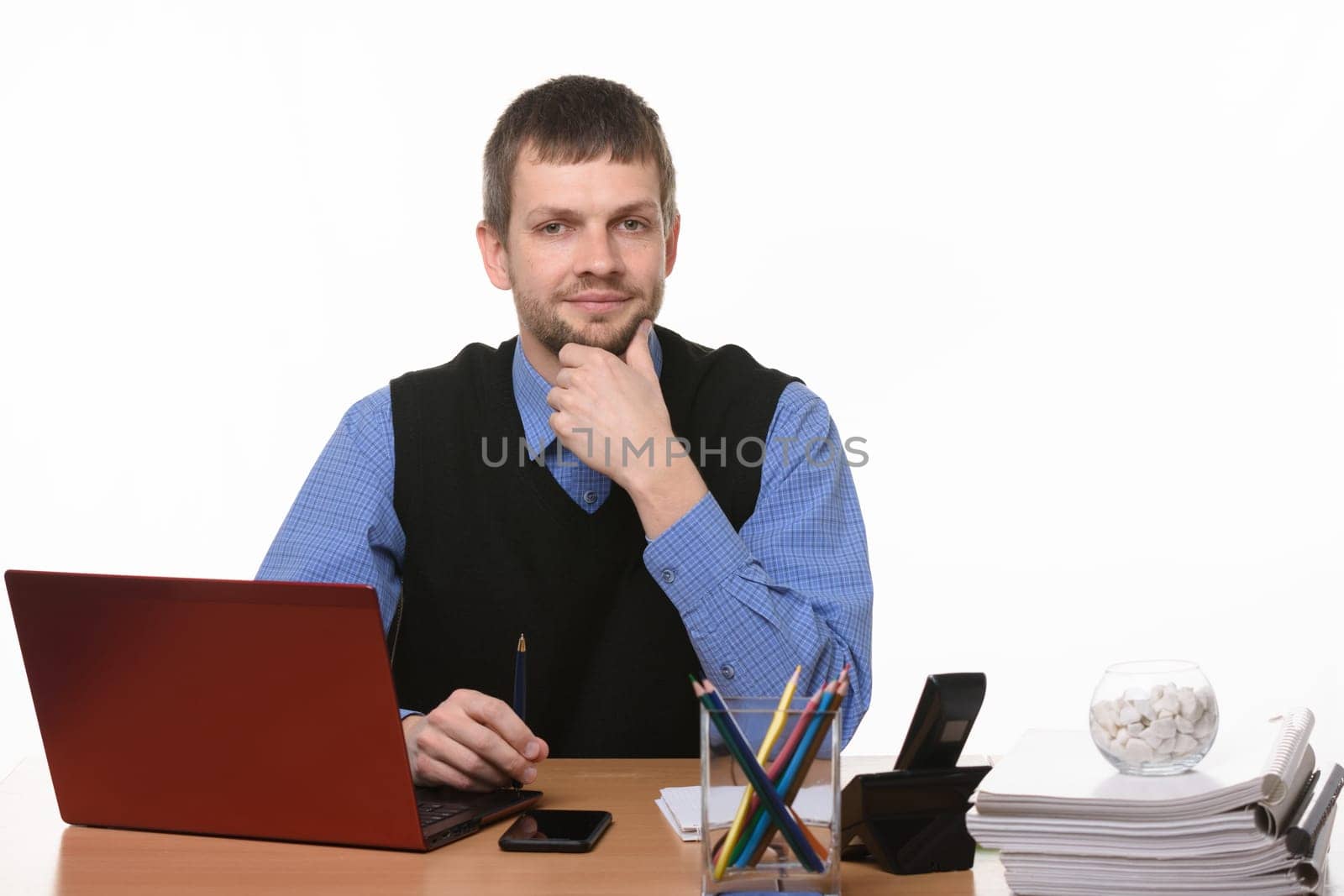 A confident man sits at the computer on a white background