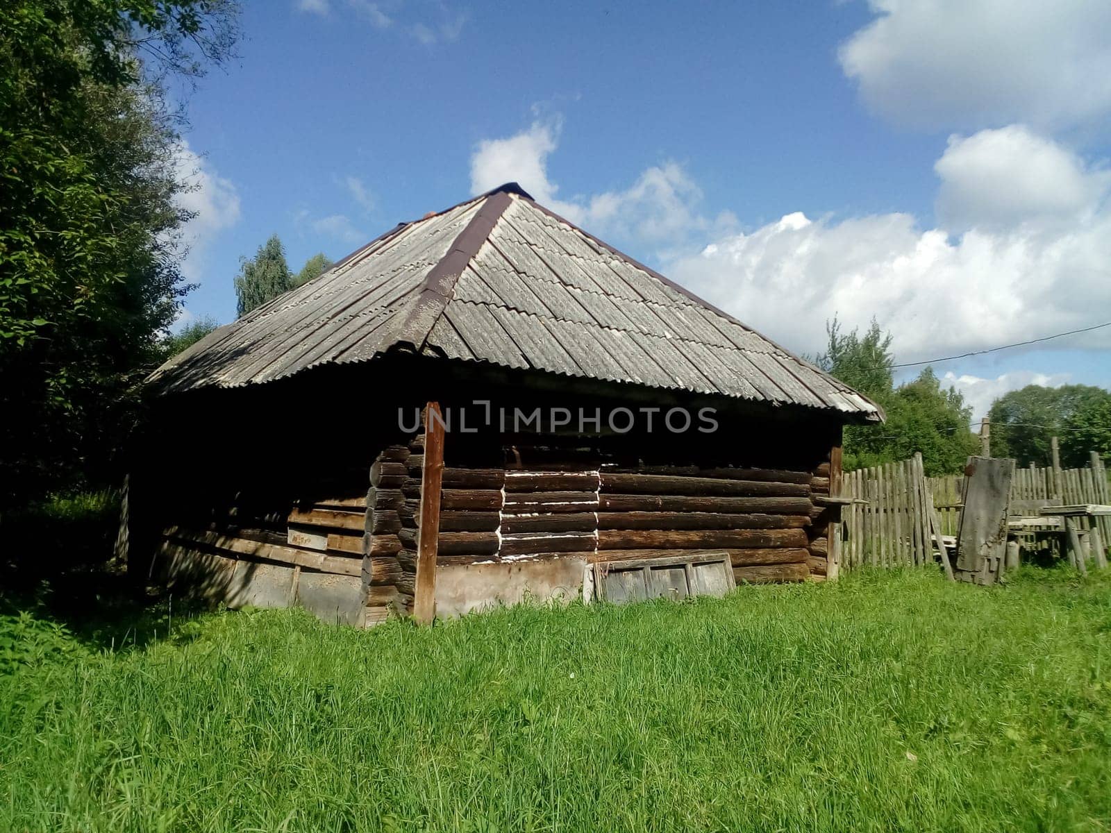 A rustic wooden house and a clearing of green grass in front of it.