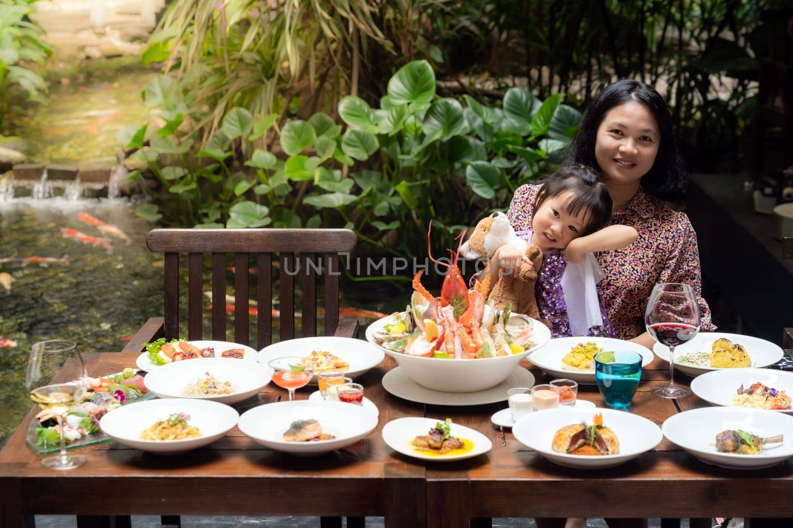 Portrait of mom and daughtersit at garden of restaurant of lobster shrimp steak beef lamb pasta spaghetti risotto rice sushi sashimi and wine using for buffet food drink background.