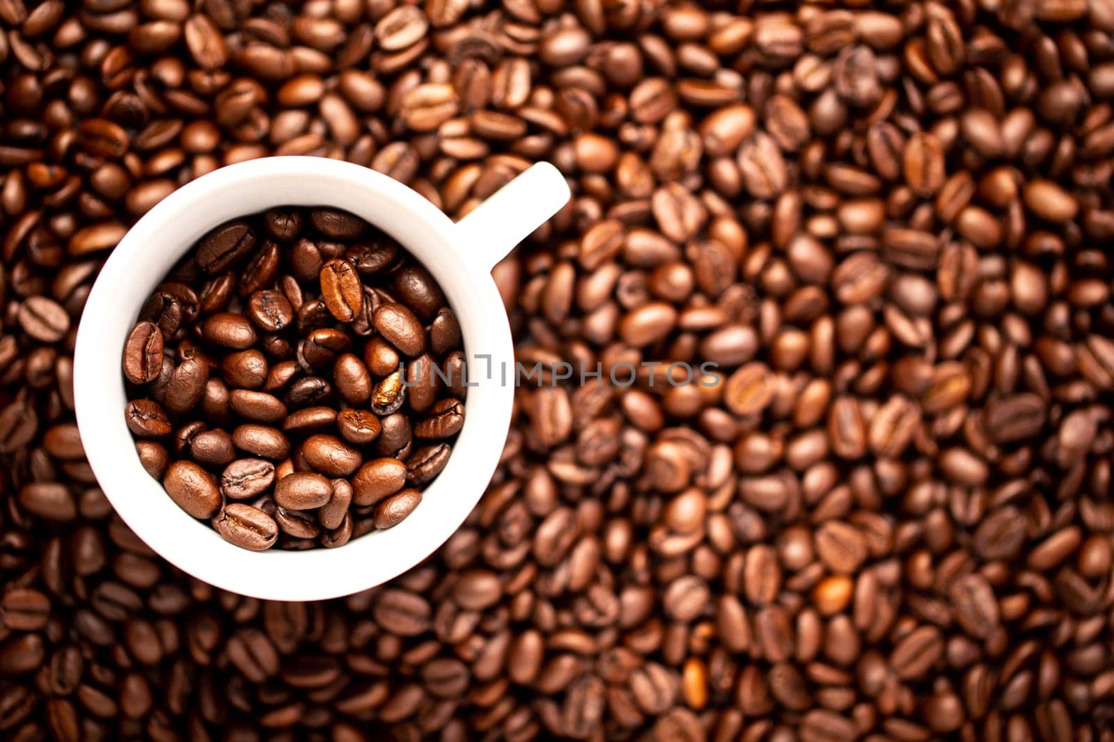 A White cup with coffee beans on a background of coffee beans
