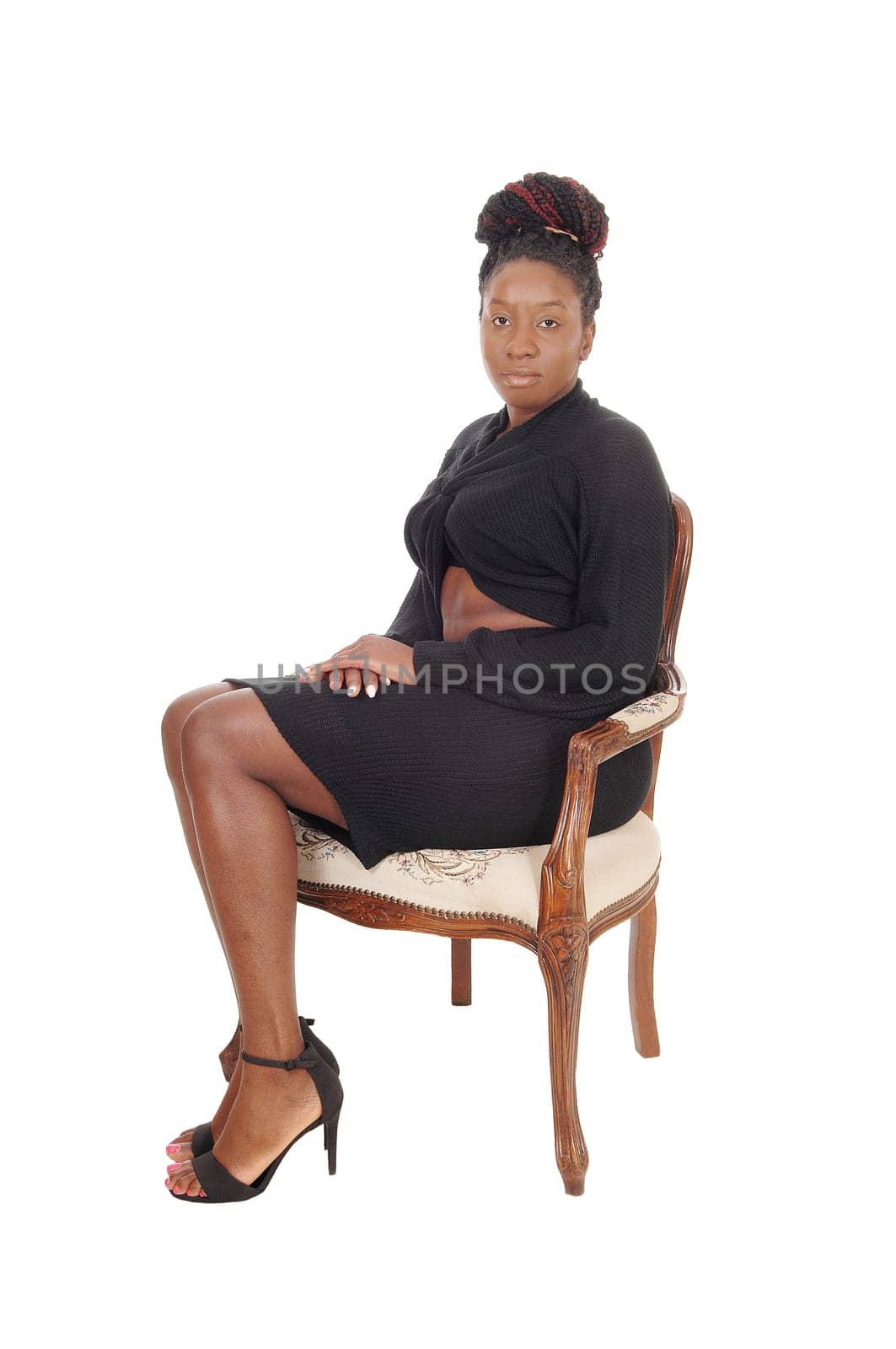 A gorgeous African American woman in a long gray dress sitting in an.old armchair, isolated for white background.