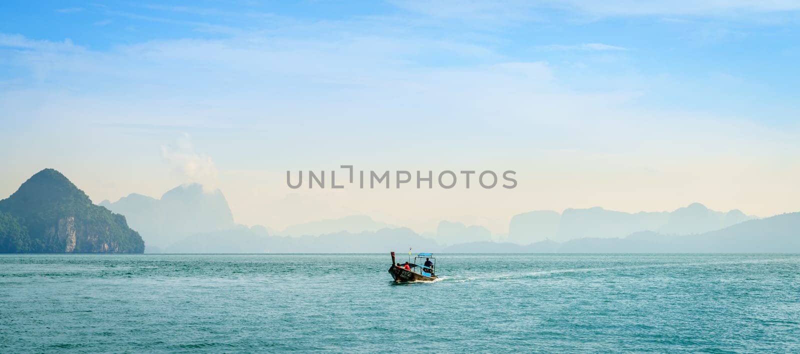 Krabi, Thailand, November 7, 2017: Traditional Thai motor boat in the Andaman Sea with Krabi coastline in the backdrop
