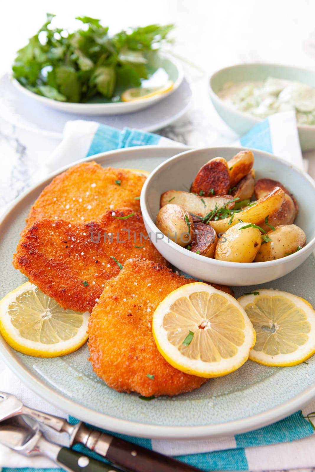 Breaded chicken schnitzel with baked potatoes and cucumber salad