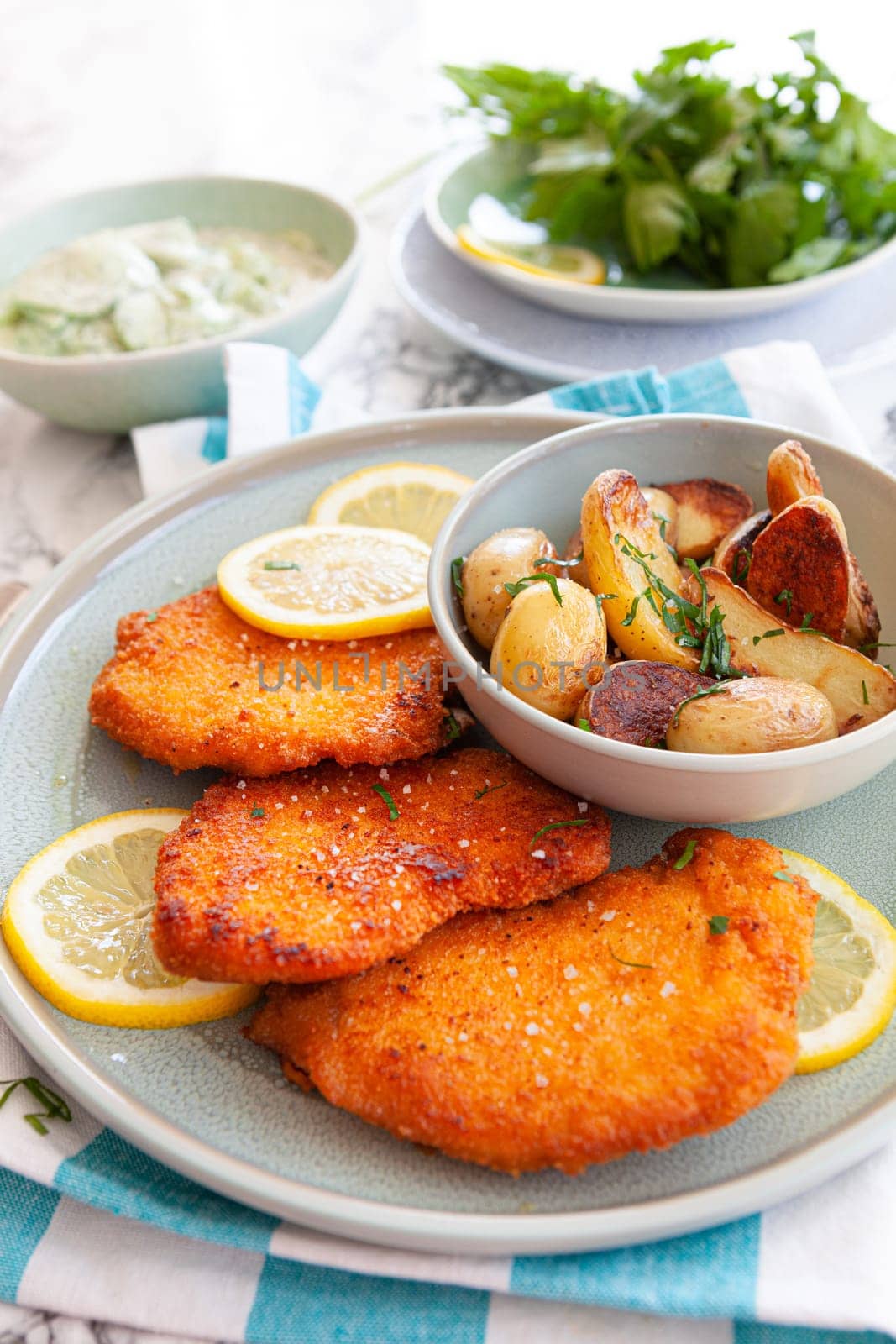 Breaded chicken schnitzel with baked potatoes and cucumber salad