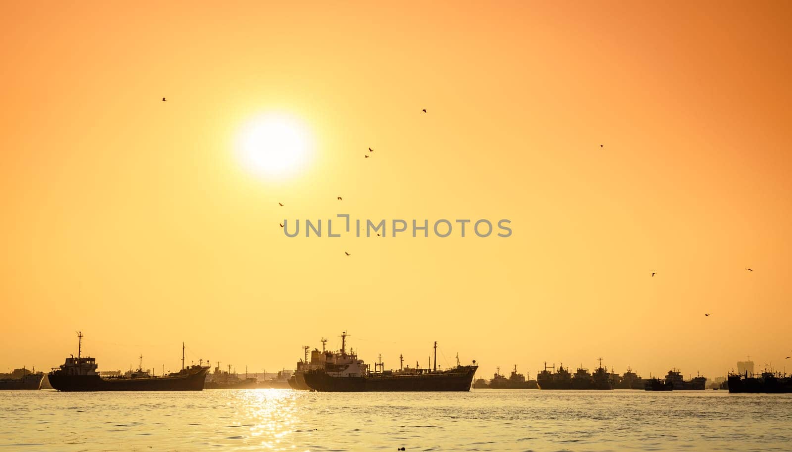 Commercial ships on anchorage in the Karnaphuli River in Bangladesh at sunset