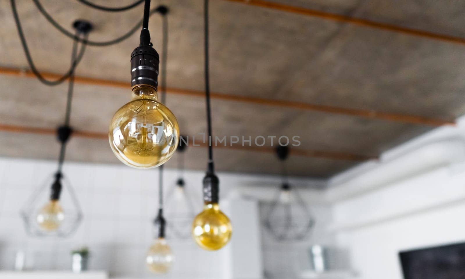 Big vintage incandescent light bulbs hanging in modern kitchen. Decorative antique edison light bulbs with straight wire. Inefficient filament light bulbs waste electricity. Dimmable, warm white, E27