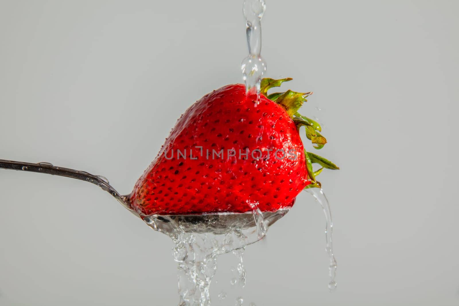 Strawberry on a spoon, being washed